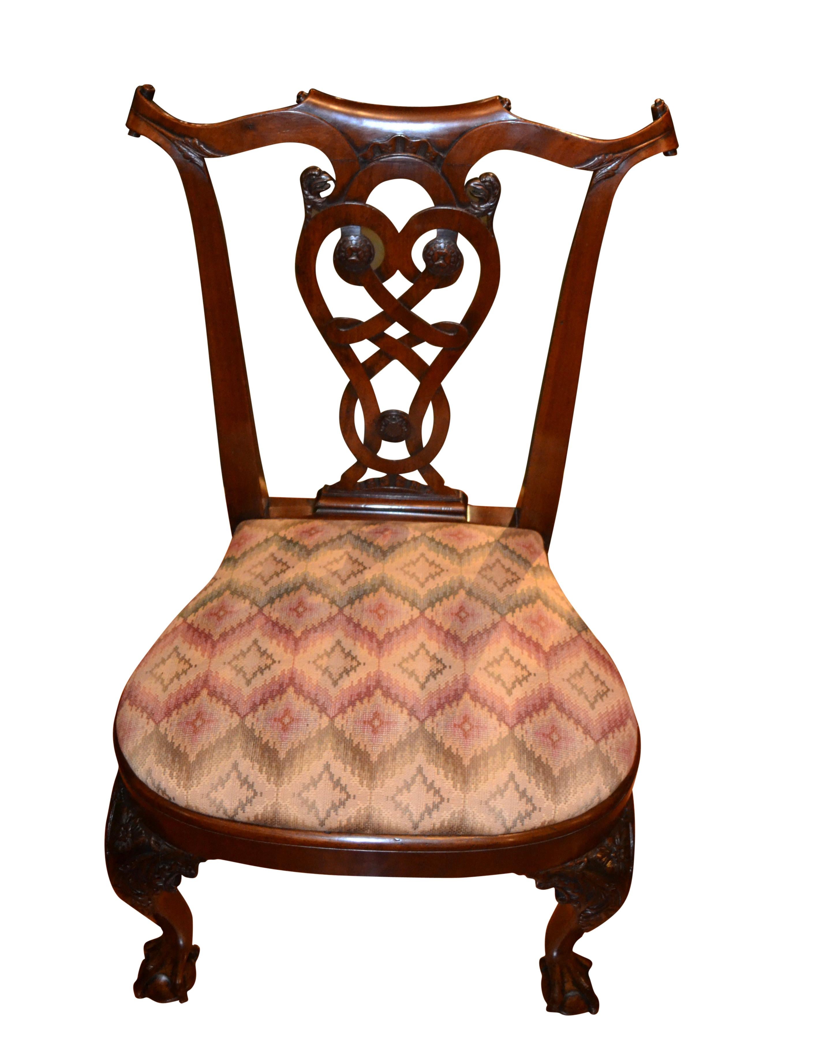 A beautifully carved stained wood open armchair in the American Queen Anne style.