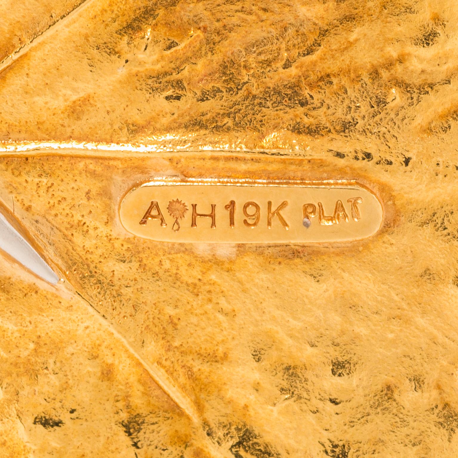 Comprising a brooch of leaf motif, with diamond-set stem, with an Aaron Henry ‘AH’ maker’s mark, set in 19k yellow gold and platinum.

2 ½ inches x 2 ¾ inches
12 round diamonds weighing a total of approximately 0.15 carat