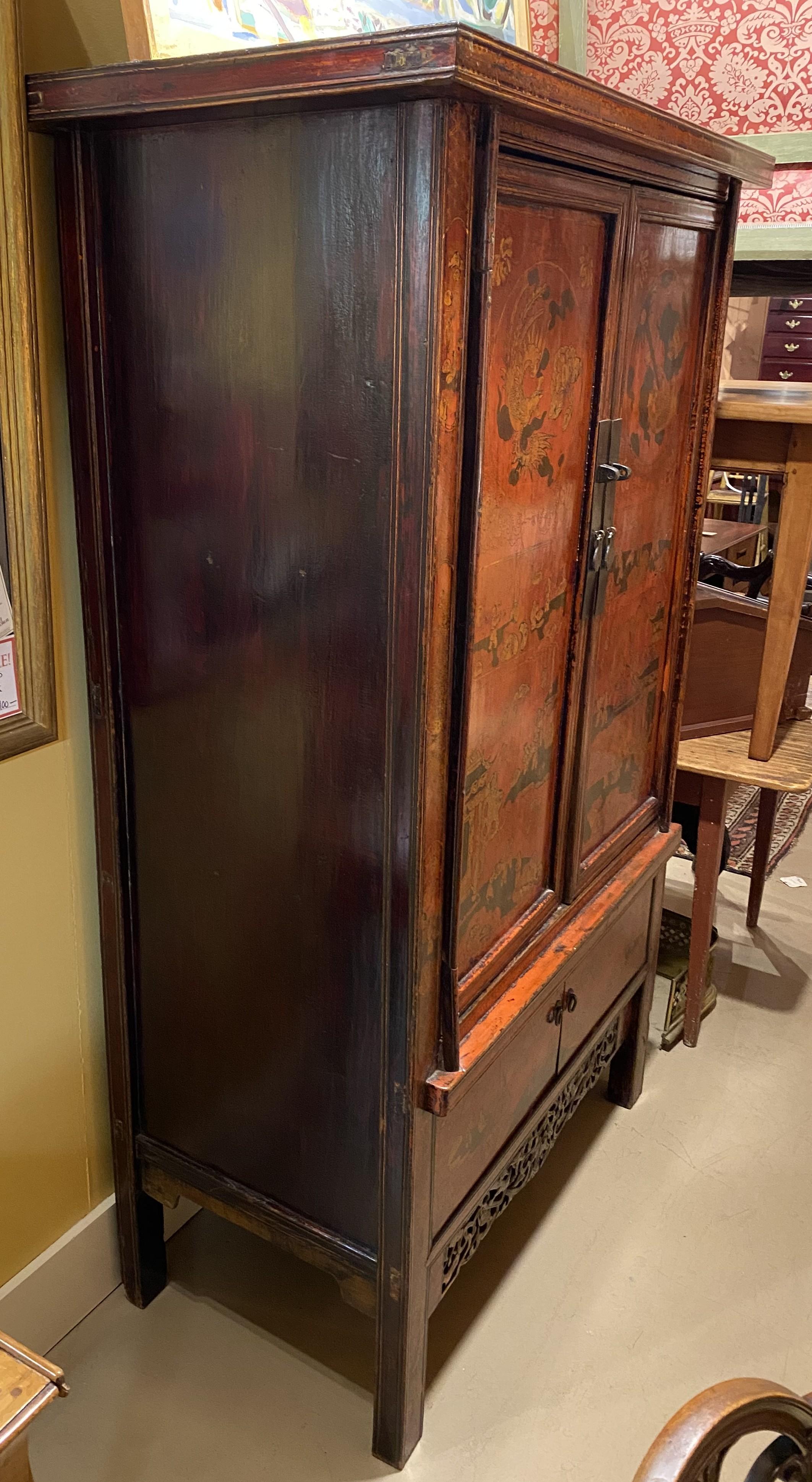 Bel exemple d'armoire ou de meuble de mariage en bois rouge et doré de style Chinoiserie, décoré de personnages et de scènes de genre avec des dragons et des fleurs, avec deux grandes portes supérieures s'ouvrant sur un compartiment de rangement,