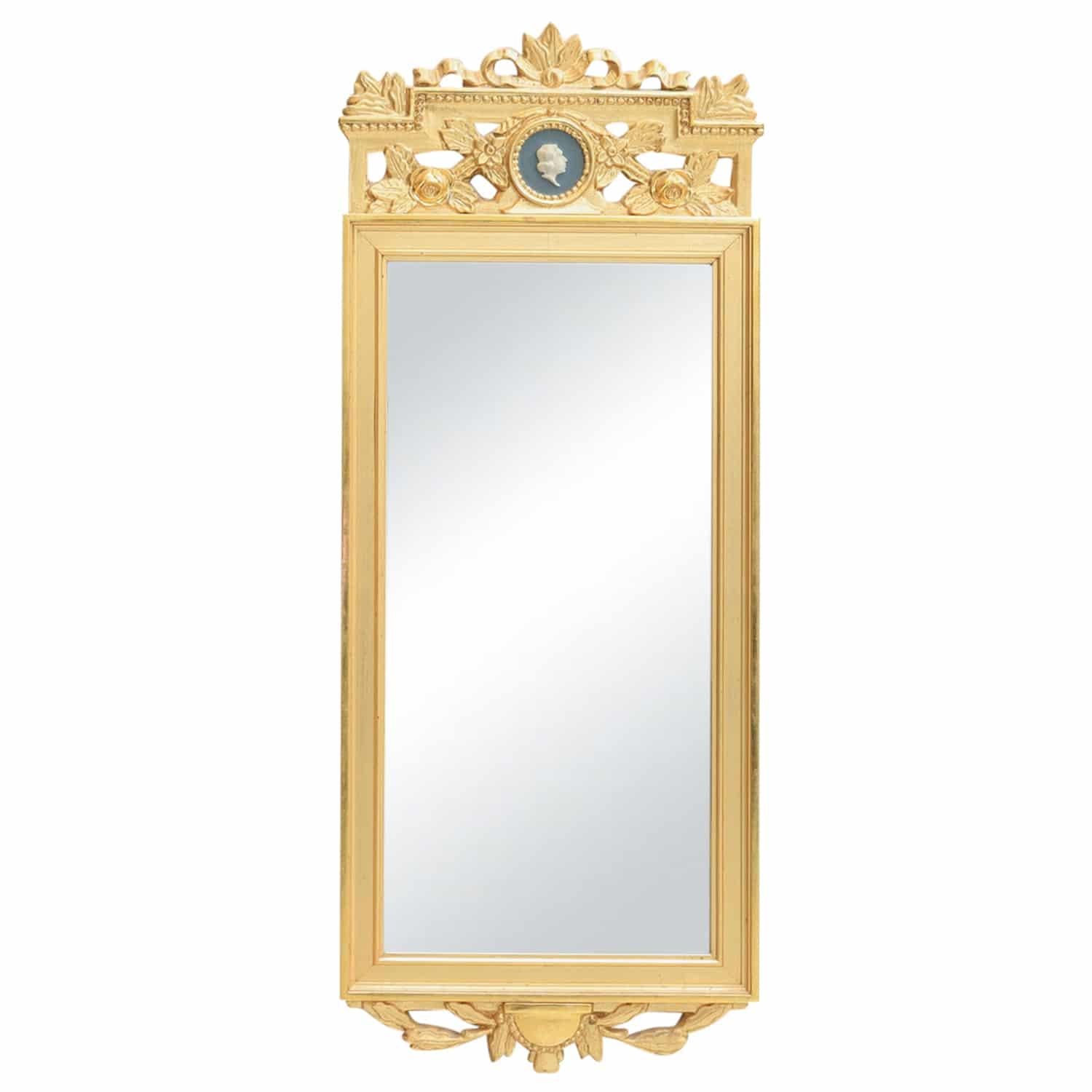 A gold, antique Swedish Gustavian wall mirror made of handcrafted gilded Pinewood with its original mirrored glass, in good condition. The particularized carved Scandinavian wall décor piece is enhanced by detailed wood carvings and fittings,