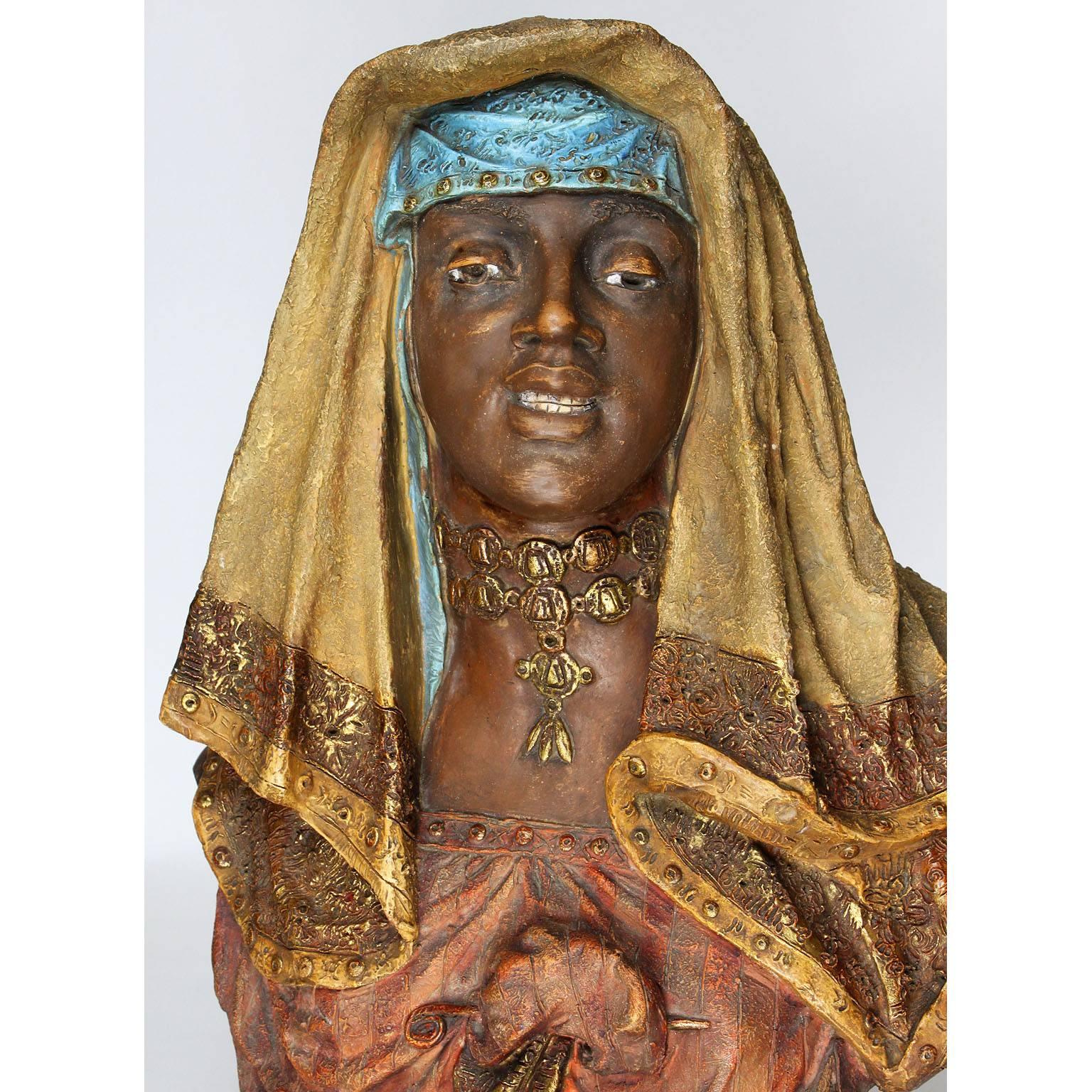 Buste orientaliste autrichien en terre cuite du 19e au 20e siècle représentant une jeune fille en tenue moyen-orientale. La jeune beauté souriante porte un chapeau et un châle noué avec une broche et des bijoux autour du cou, sur un socle circulaire