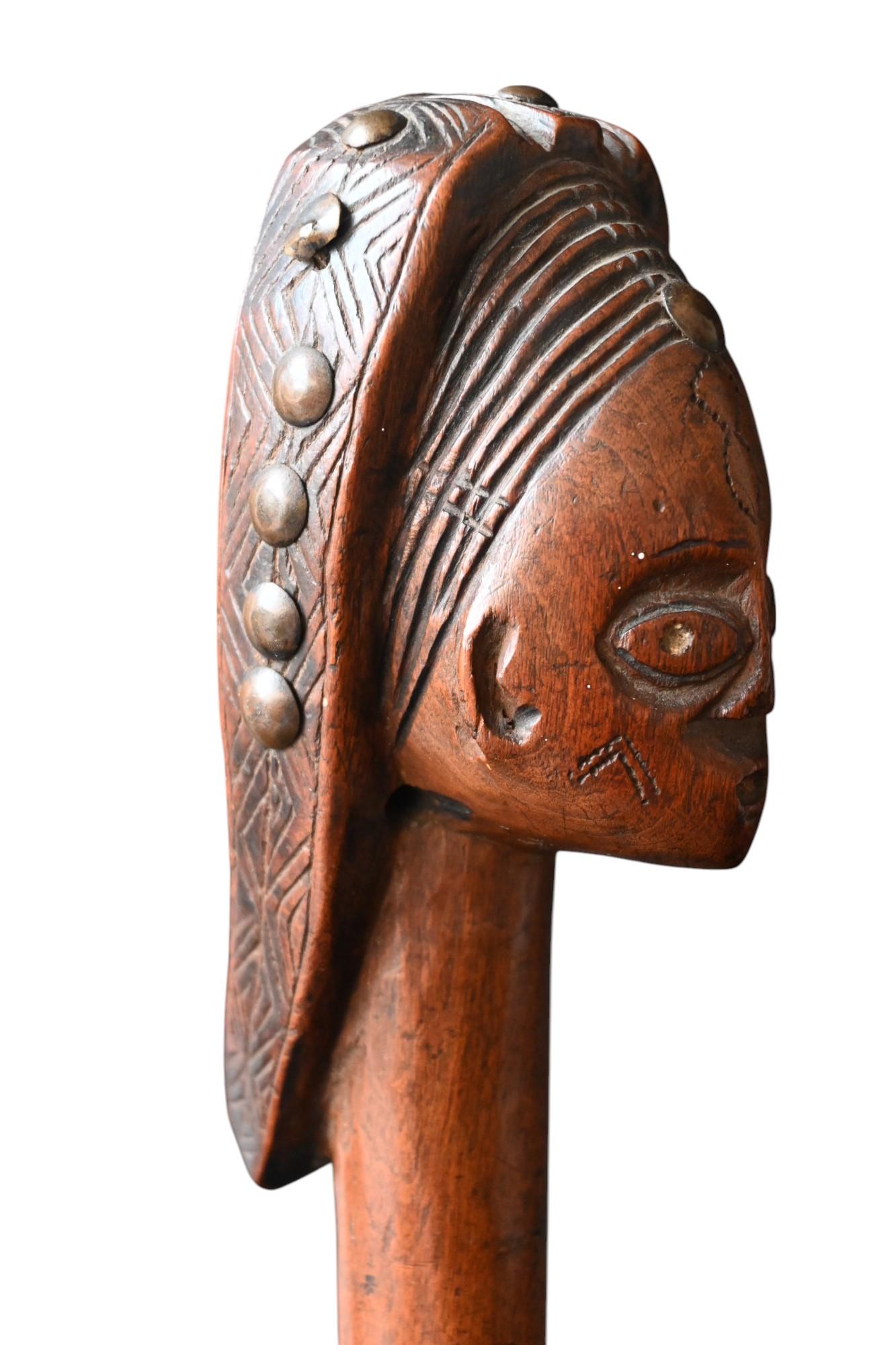 Description:
A striking carved wooden staff finial from the Ovimbundu people of Angola, dating from the late 19th to early 20th century.

This finely sculpted piece depicts an idealized female head, with an elongated neck, large almond-shaped eyes,