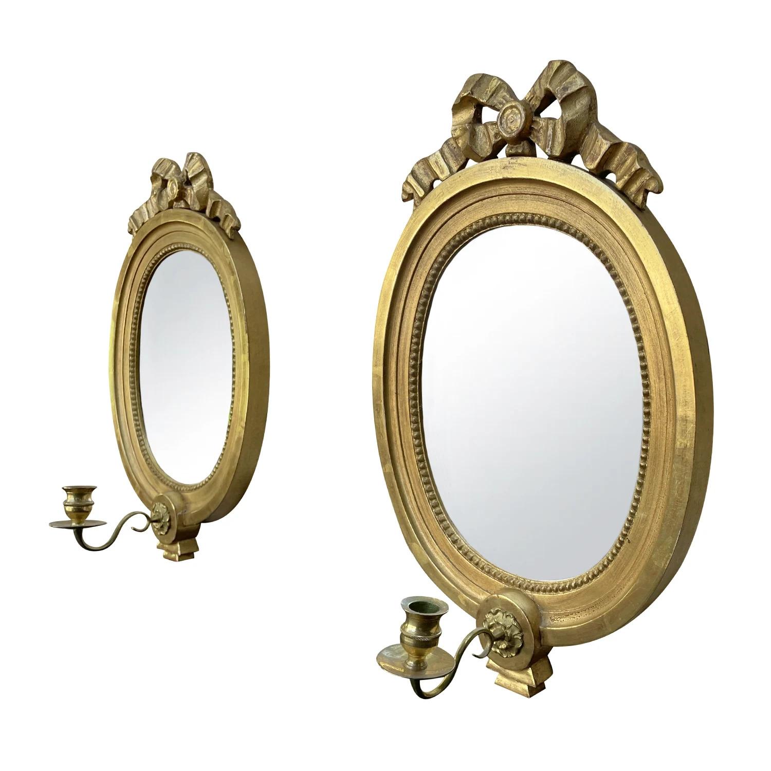 A 19th - 20th Century, gold antique Swedish Gustavian style pair of oval shaped wall mirrors made of hand carved gilded wood, bronze with its original mirrored glass, in good condition. Each of the Scandinavian wall décor piece is composed with a