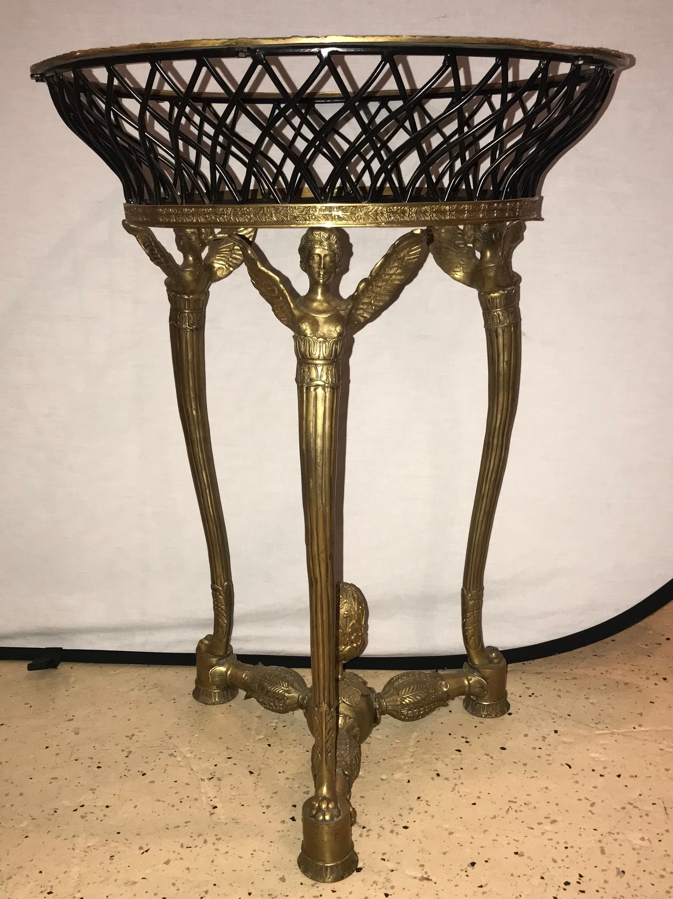 A 19th or early 20th century Empire bronze basket or jardinière on figural gilt bronze stand. The bronze framed ebony weaved basket having a group of three triangular shaped winged woman on small pedestals all in a gilt bronze. This finely cast