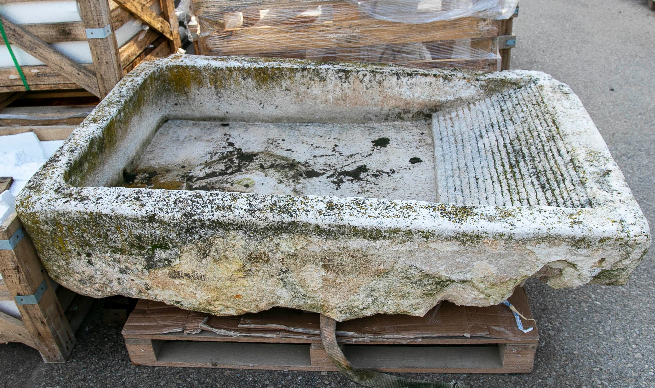 Hand-carved antique stone laundry basin with a beautiful natural patina created by time. Its weathered surface, moss, and irregular textures lend it an authentic and rustic character. Ideal as a water feature, planter, birdbath, or outdoor