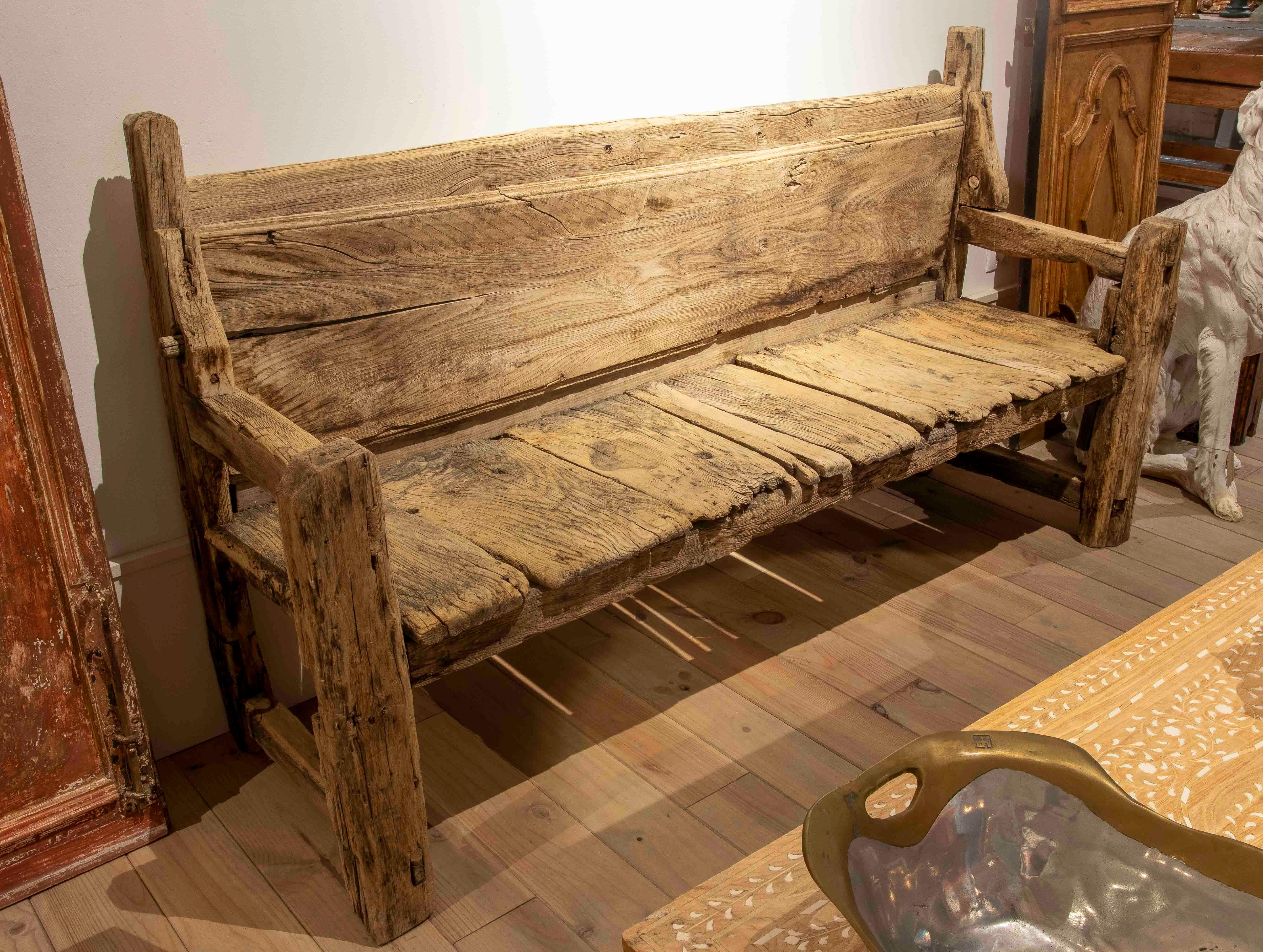 Antike Bank aus Massivholz, mit einem robusten und authentischen Design, das seine ursprüngliche Patina und seinen Charakter im Laufe der Zeit beibehält. Rückenlehne und Sitzfläche sind aus dicken, handgeschnitzten Bohlen gefertigt, deren rustikales