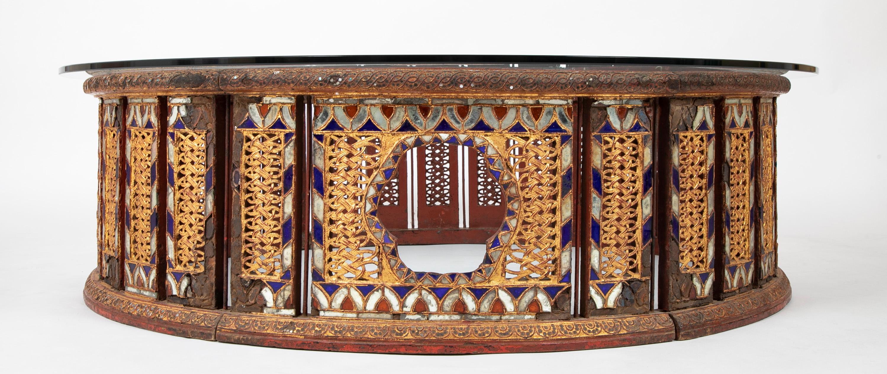 A very cool large scale round coffee or cocktail table, late 19th century, Burma (now Myanmar). Designed as six openwork curved panels that join to form a circle, connected by iron hinges with cotter pins, with a later glass top. Decorated with