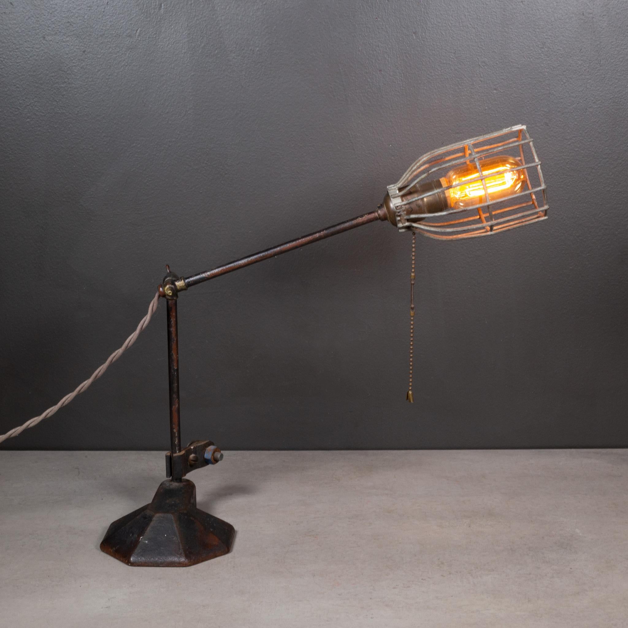 ABOUT

An antique adjustable industrial caged table lamp with cast iron base, bronze centerpiece and original fabric cord. The arm adjusts at any angle and can be angled straight up.

 CREATOR Unknown. 
 DATE OF MANUFACTURE Late 1800s.
