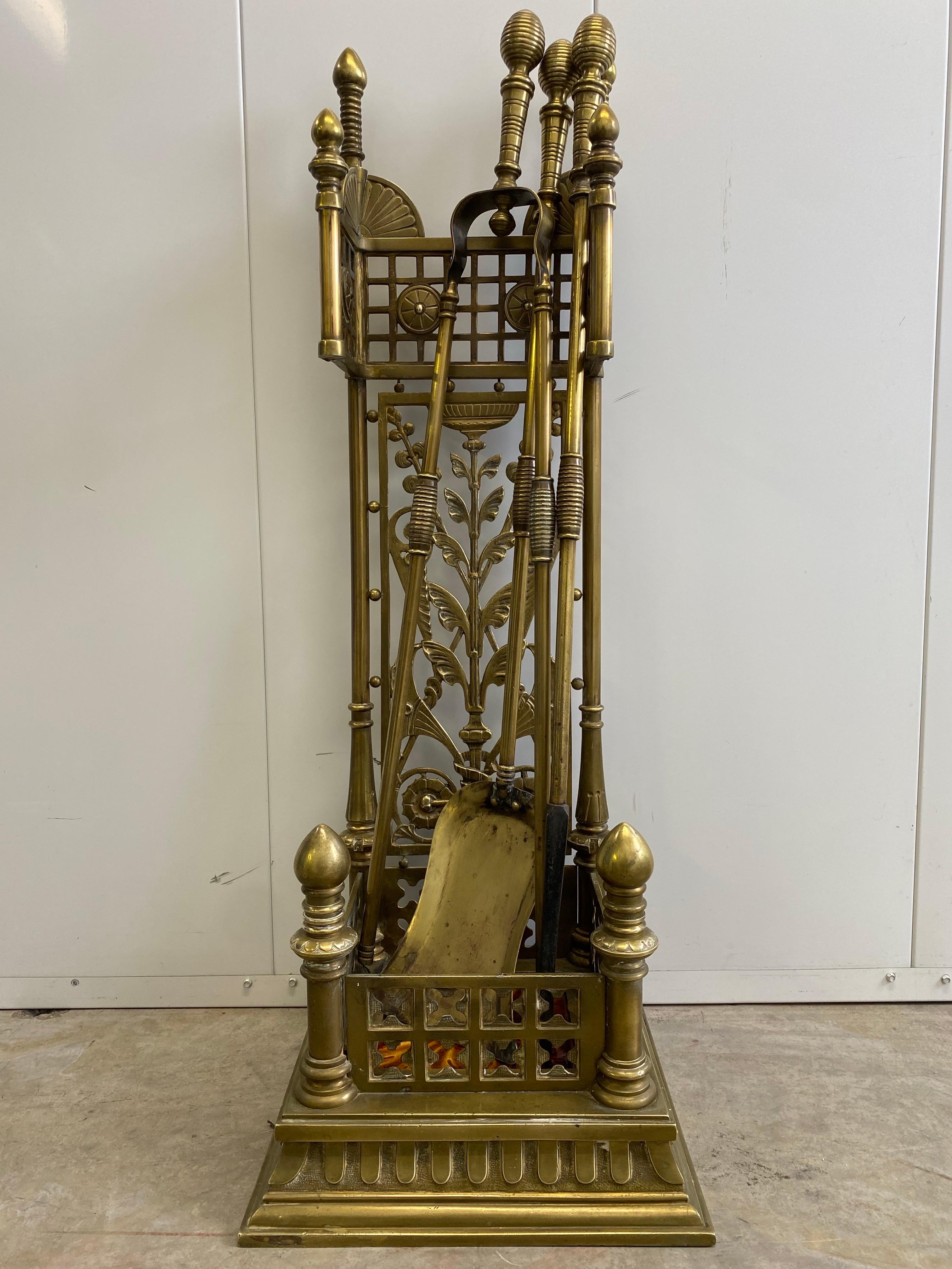 A highly uncommon, full set of high style Aesthetic Movement brass fireplace tools in their original stand. This stand features a Kensington Tile in its base which points towards American manufacture. The quality of the casting and their design