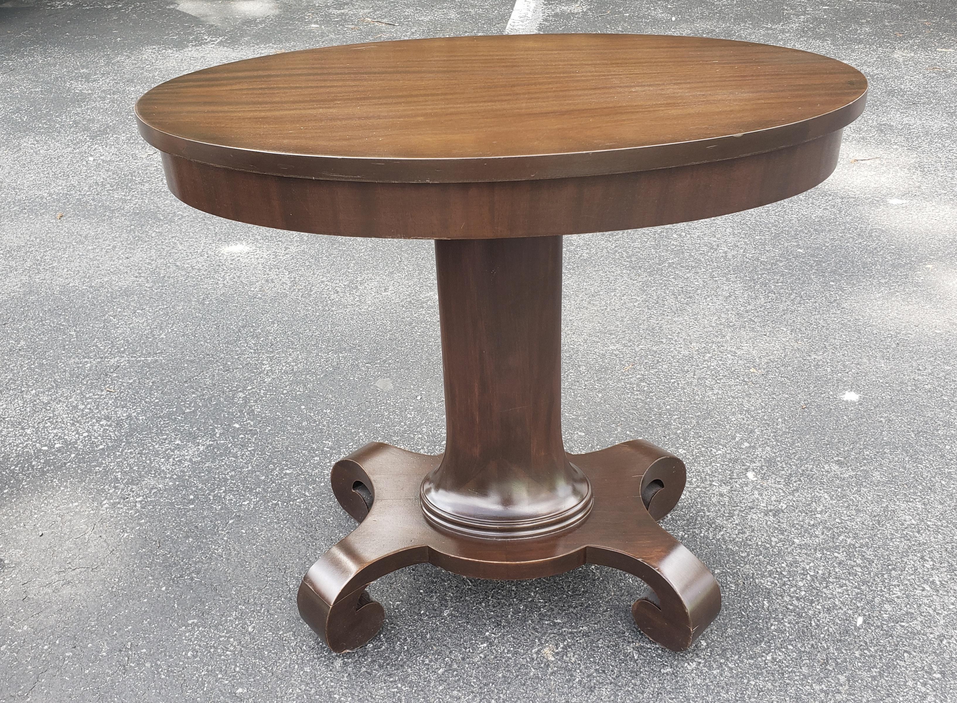 A newly and fully refinished solid mahogany American Empire Oval Pedestal side table. Features four large scroll feet under the Pedestal. Hand Rub refinished. May be used as a side table, center table, as a hall table as a library table or as plant