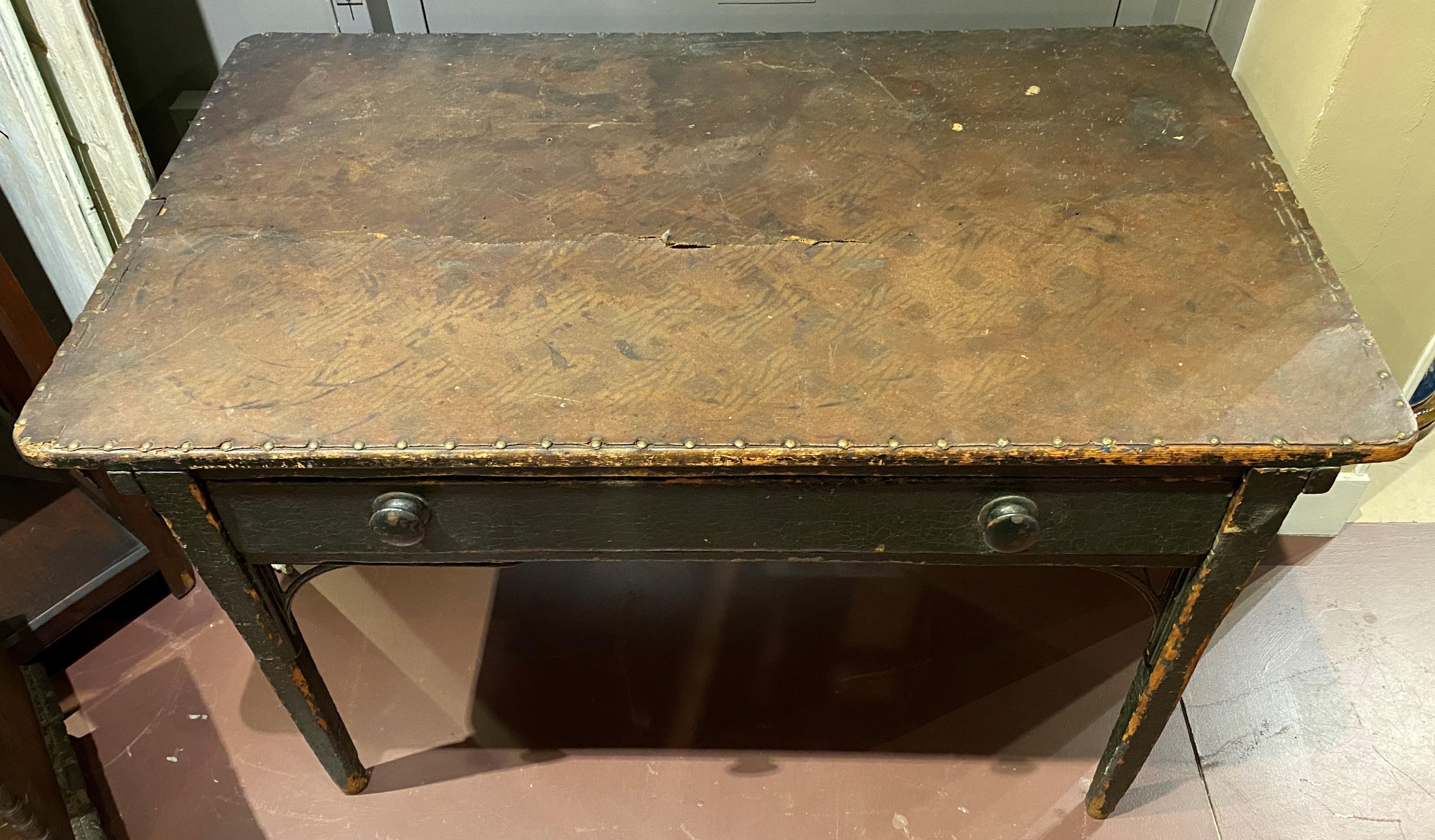 A fabulous 19th century American Industrial wooden rectangular one drawer work table in old green paint, with metal front leg support brackets, and a lined top made of leather-like canvas material with woven backing, attached with brass upholstery