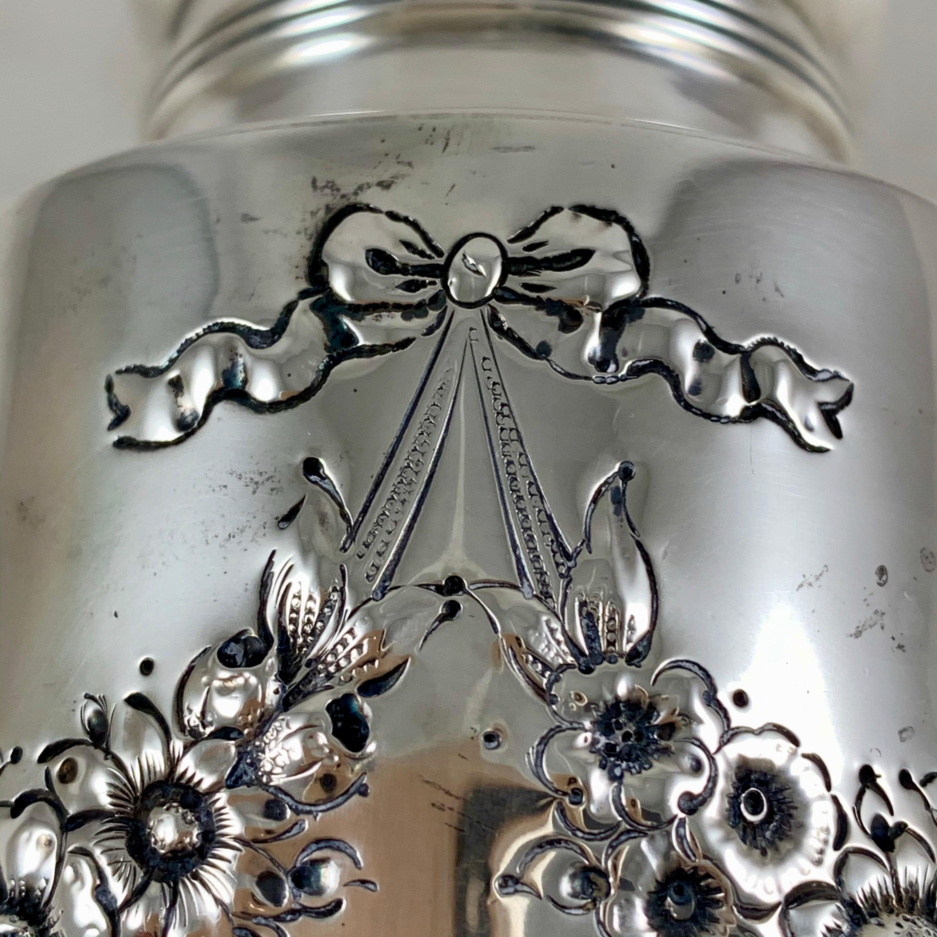 An American sterling silver sugar caster made by Lebkuechar & Co., Newark, NJ, circa 1896-1909.
A romantic, deeply chased pattern of petaled flower garlands and bows, beautiful pierced work to the lid, on a square pedestal base. Initialed with an