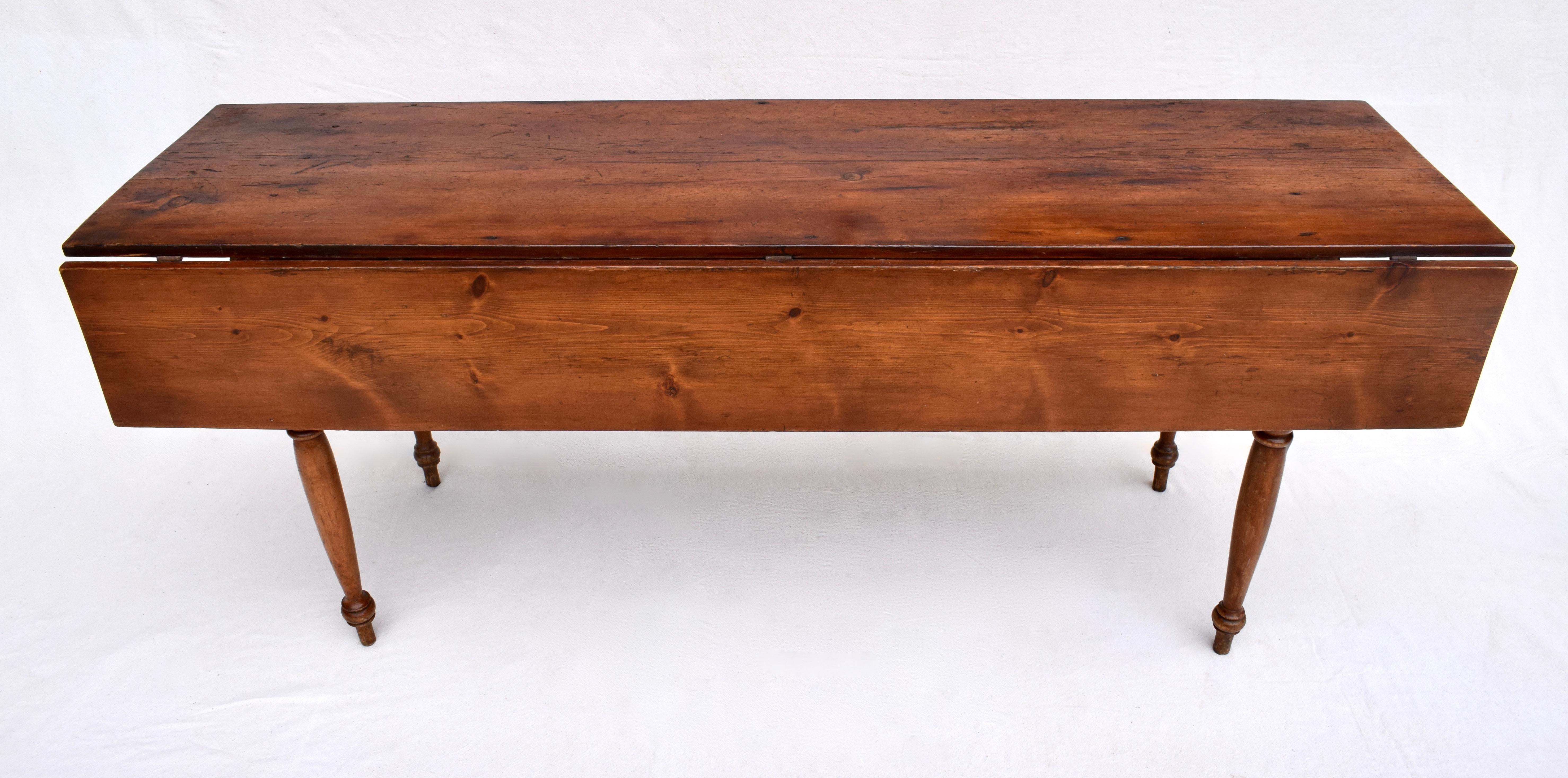 19th c. American drop leaf pine harvest farm table with finely turned peg constructed legs. Depth of table with leaves closed: 20.75