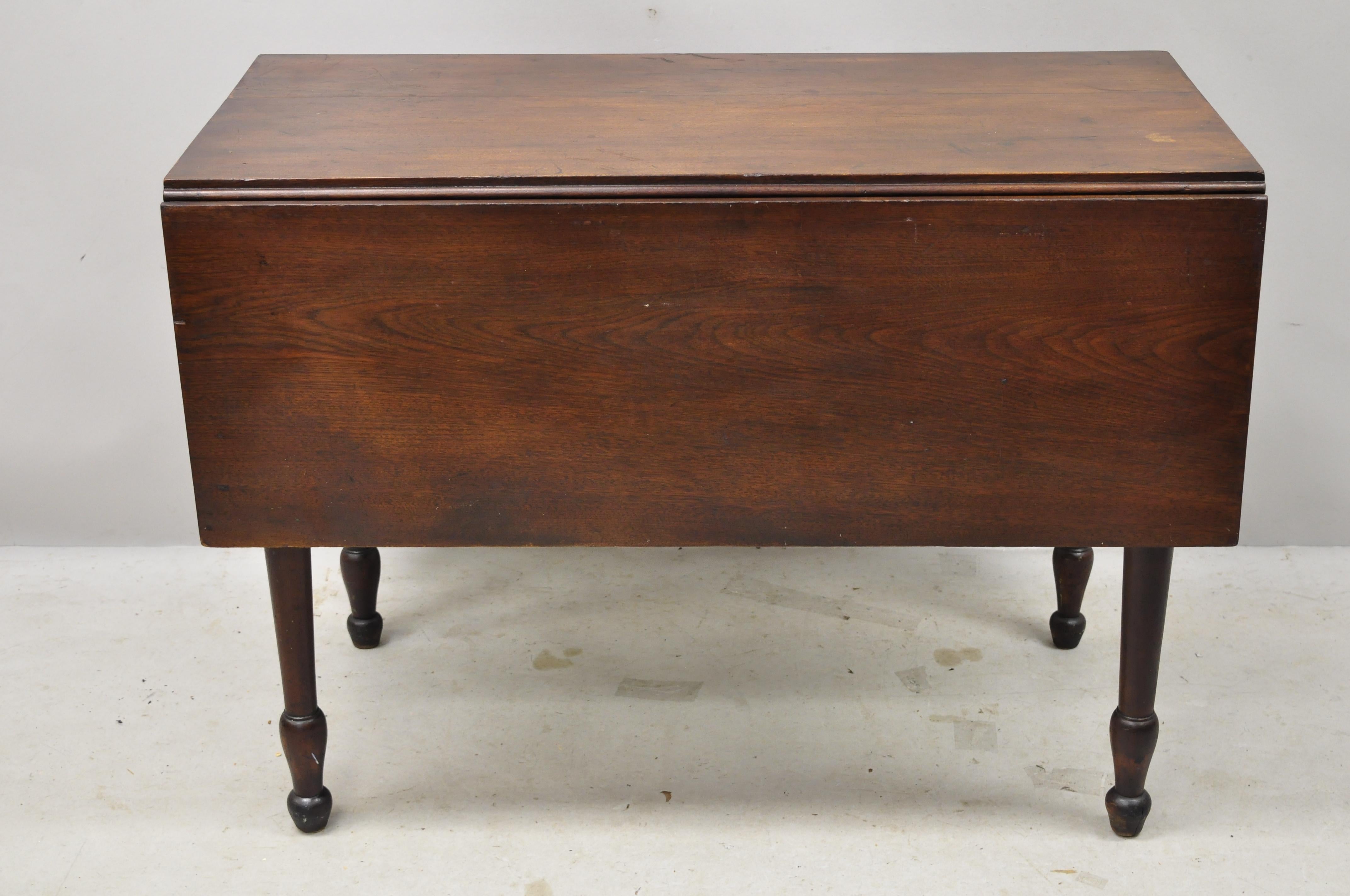 19th century American Primitive colonial drop leaf walnut breakfront dining table. Item features drop leaf sides, turn carved legs, solid wood construction, beautiful wood grain, very nice antique item, quality American craftsmanship, circa 19th