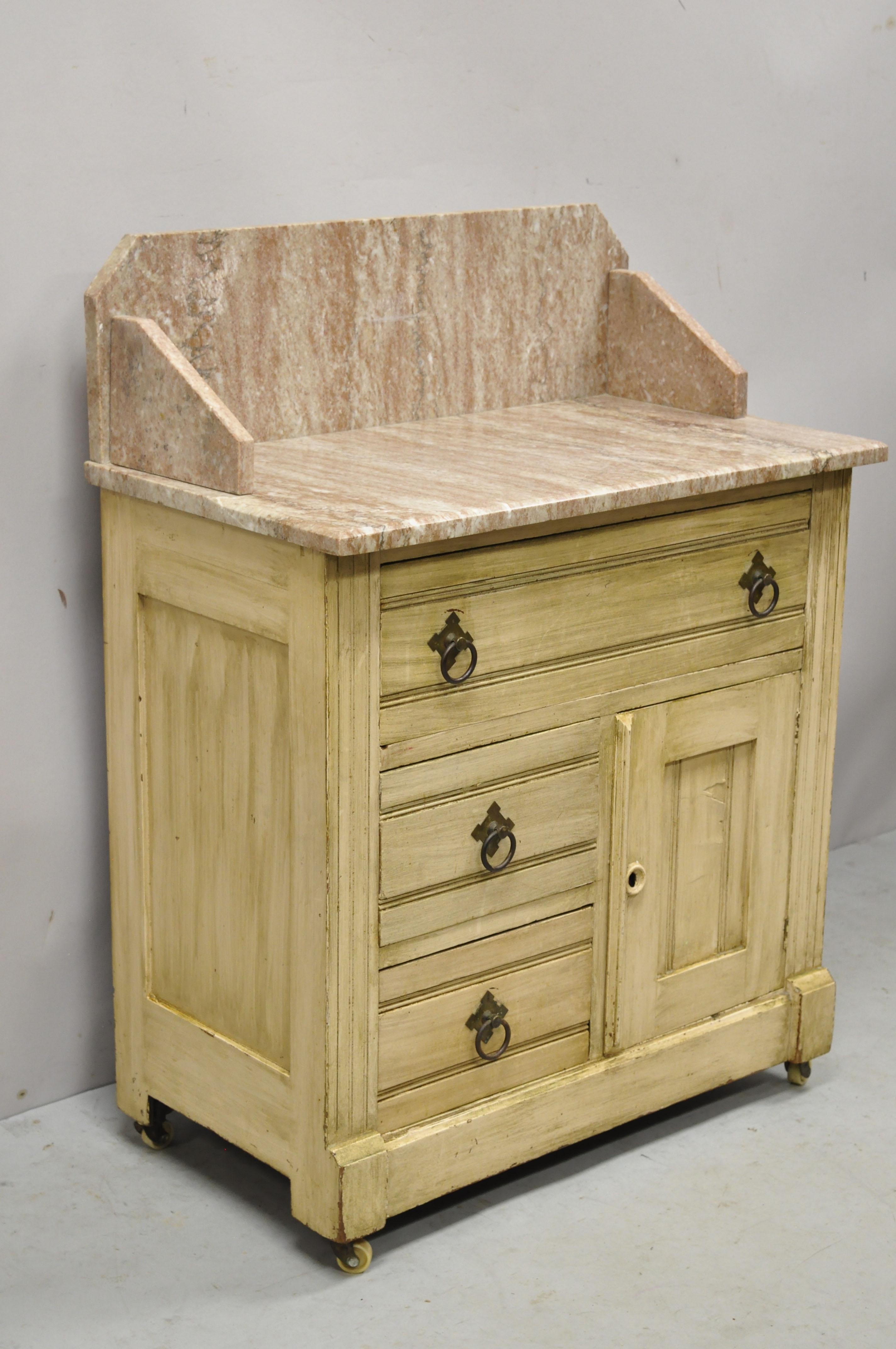 Antique 19th Century American Victorian pink marble top backsplash washstand table cabinet. Item features pink marble backsplash, 1 swing door, no key, but unlocked, 3 dovetailed drawers, solid brass hardware, very nice antique item, quality
