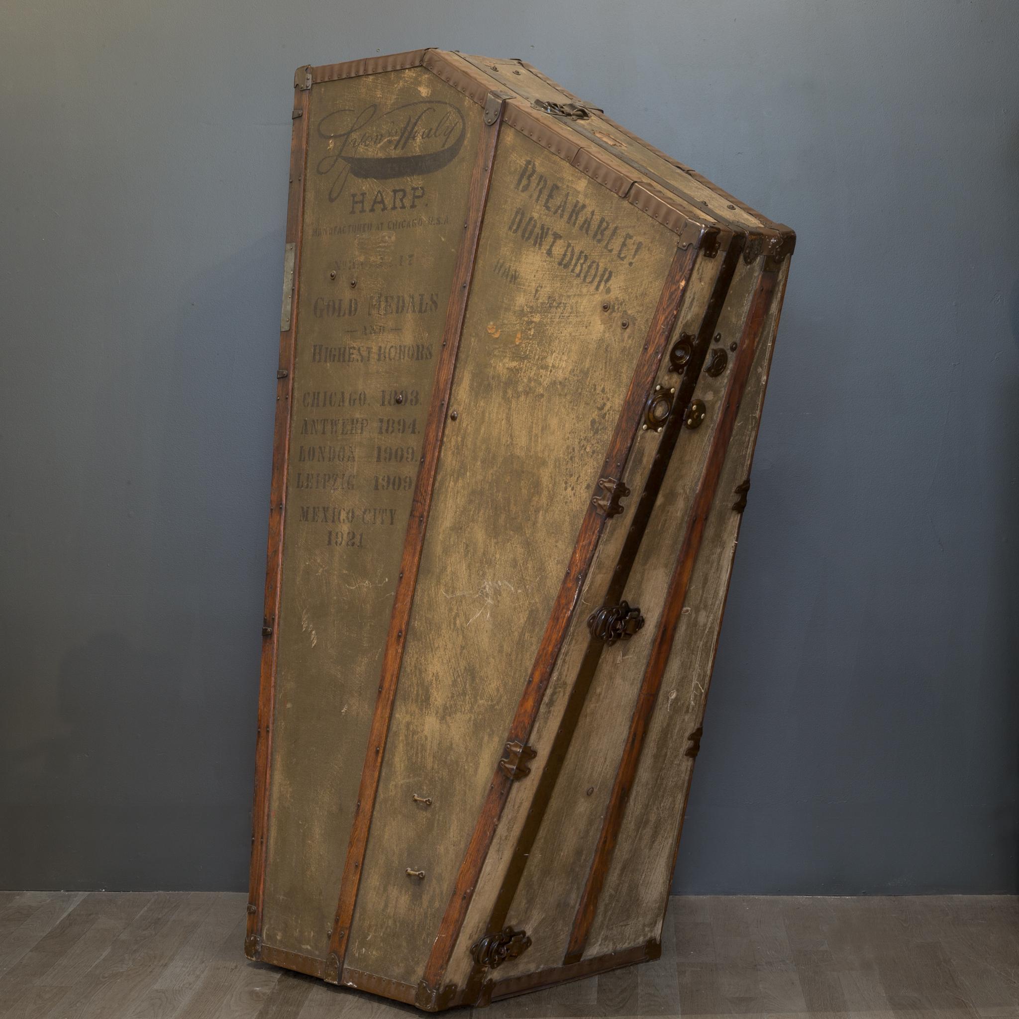 This is an original professional touring harp case. The case is covered in canvas and trimmed in wood and metal cladding. The touring dates and cities are stamped on both sides and range from 1893-1921. The cities vary from London, Leipzig, Chicago