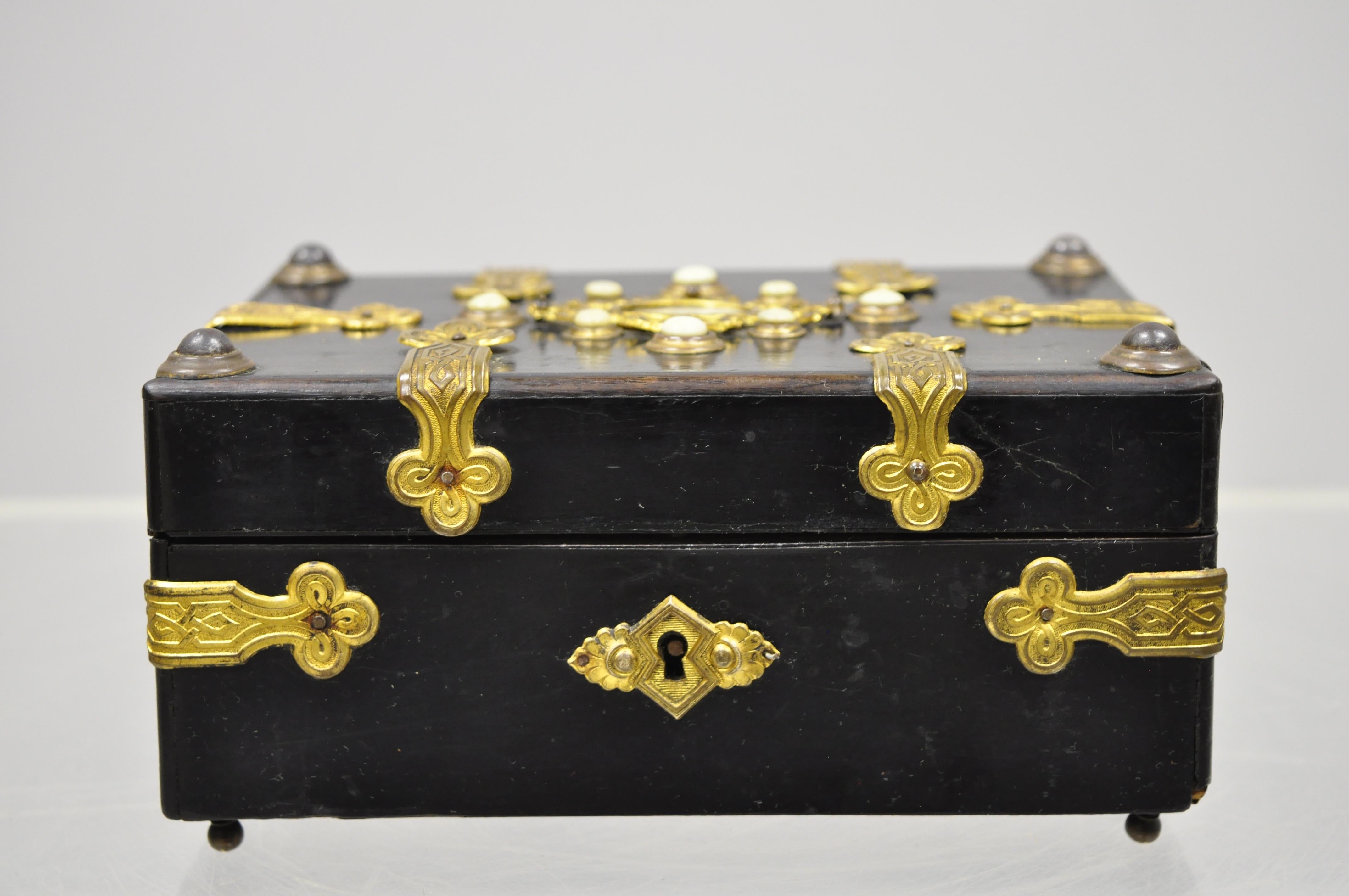 19th century antique English ebonized brass bound jewelry trinket box. Item includes an engraved brass bound case, mother of pearl accents, felt lined interior, raised on small feet, no key, but unlocked, very nice antique item, circa late 19th