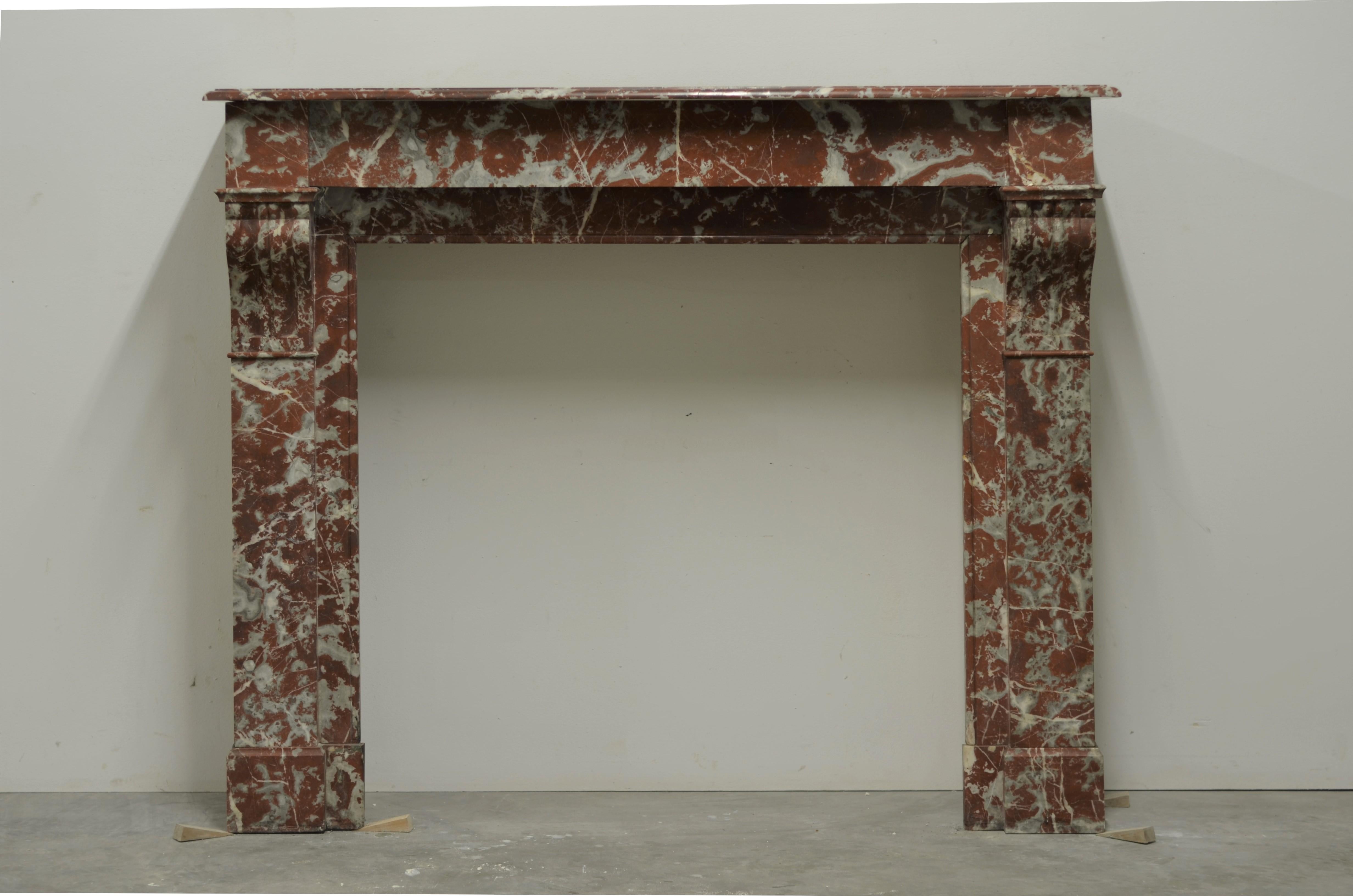 Lovely decorative Parisian fireplace mantel with nicely carved corbels.
Executed in Belgian red marble this mantel was installed in a nice sized Parisian bedroom.

Original condition, ready to be shipped an installed.