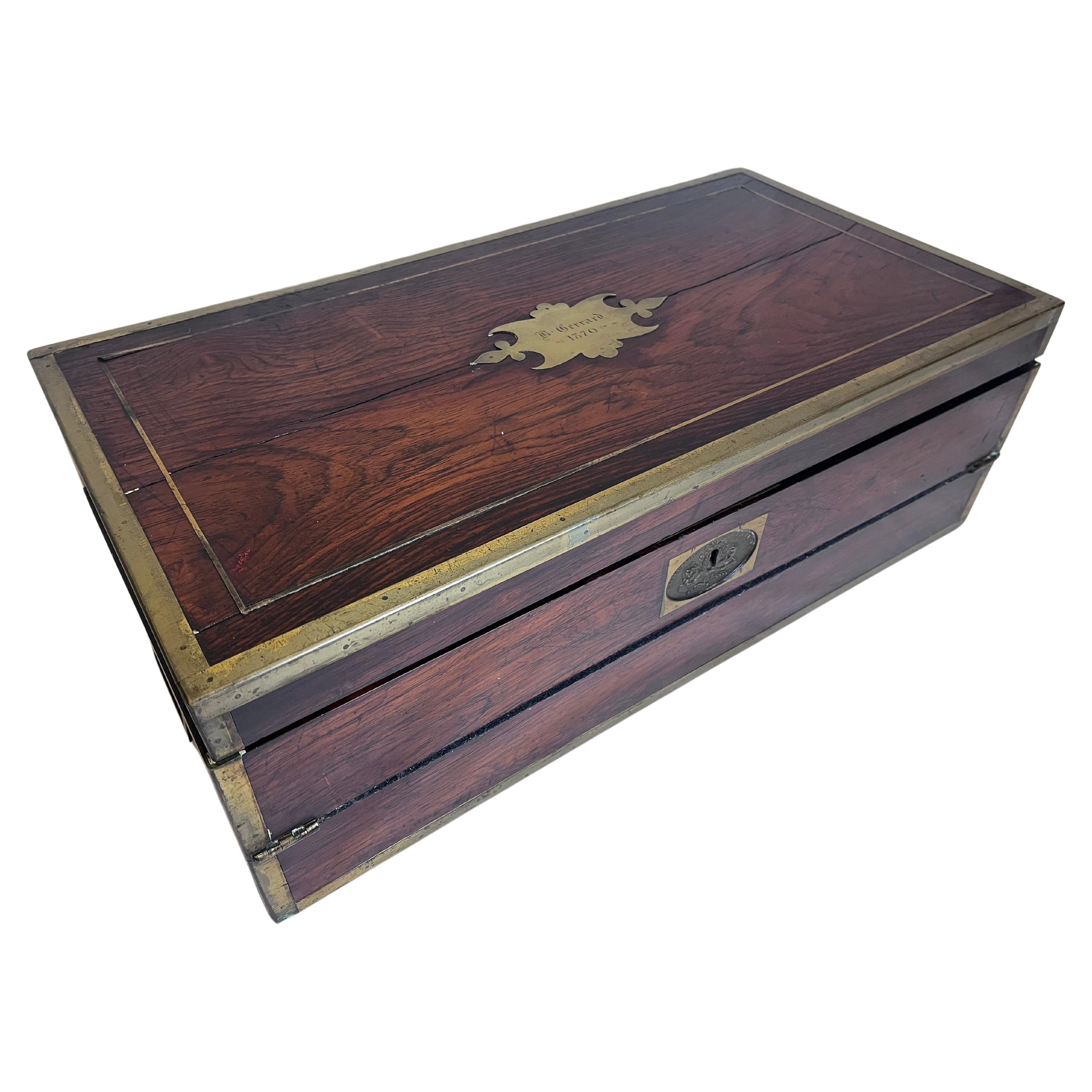 An antique, circa mid 19th Century English Military Campaign traveling writing or lap desk with brass details, a fitted leather and gilt interior, two ink bottles, pen tray and compartments under the fold out writing area. The campaign desk features