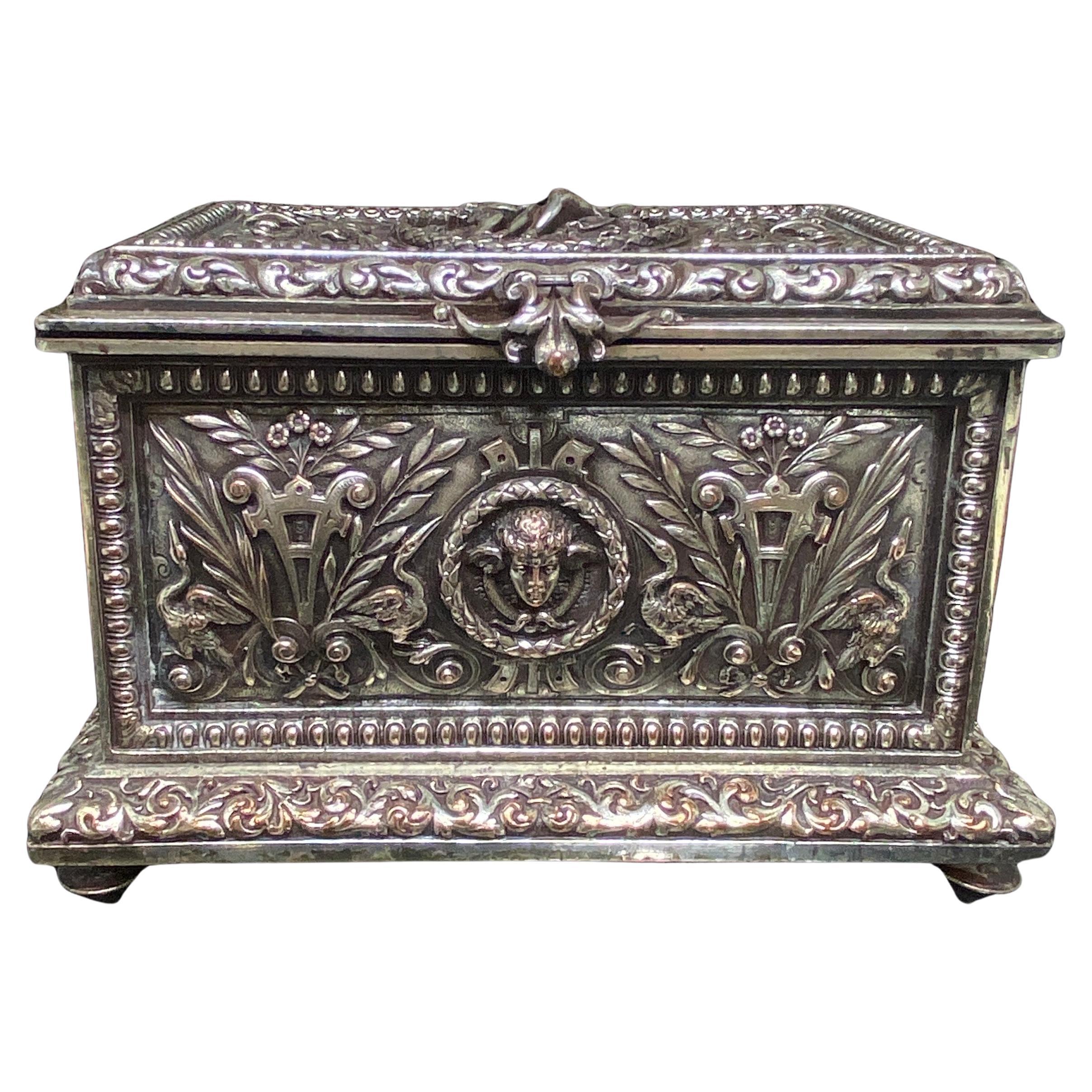 Up for your consideration is this impressive 19th century silverplated bronze trinket, jewelry box, cask.

It features an allover high relief neoclassical repouse design of winged caryatids, florals, urns, snakes, cherubs and egrets.  Each side is a