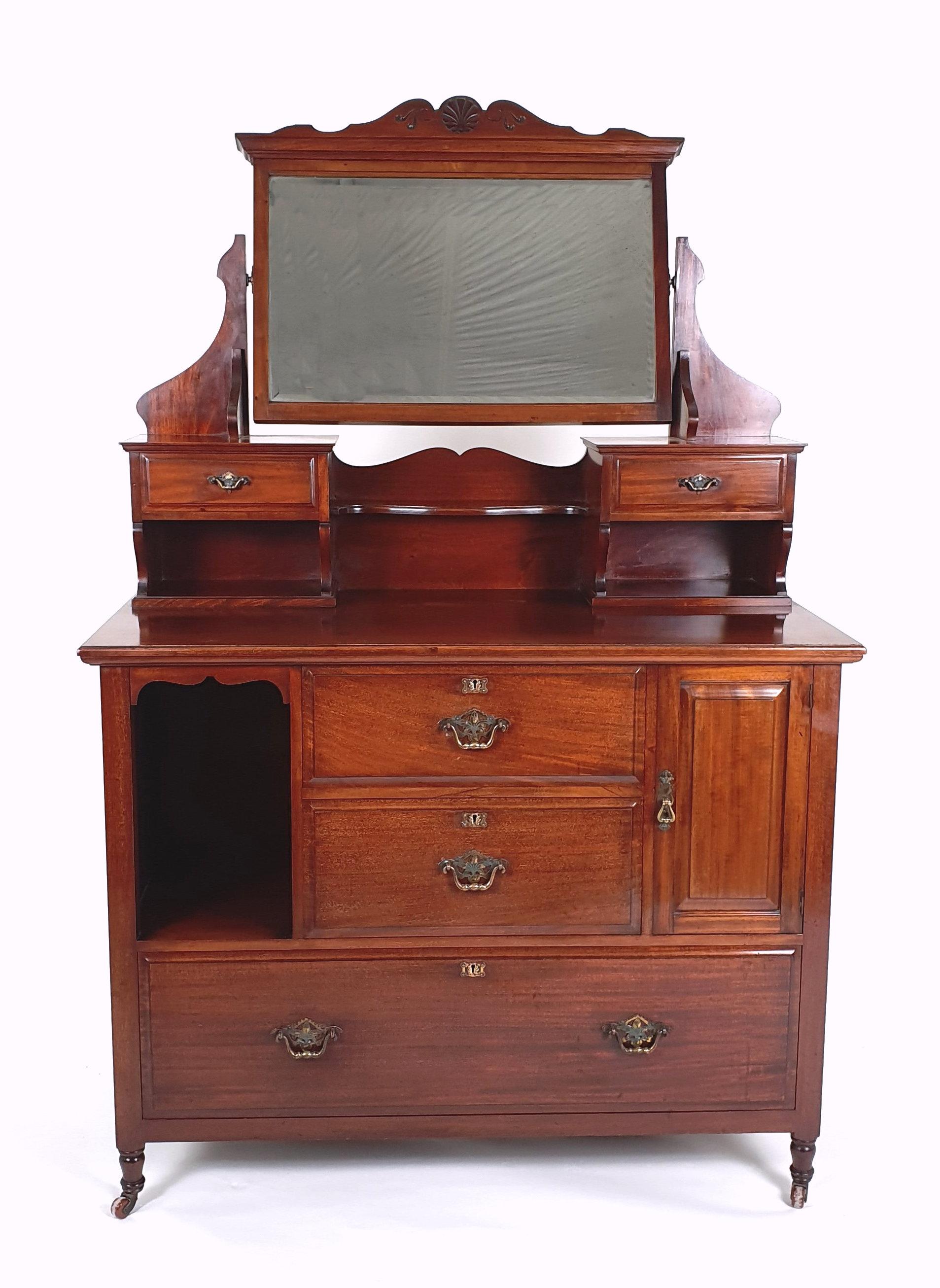 This very handsome and solid Art Deco walnut dressing chest features the original pierced brass handles and original ceramic castors. The dressing chest has an adjustable mirror on top flanked on either side by a jewellery drawer. There are 2 short