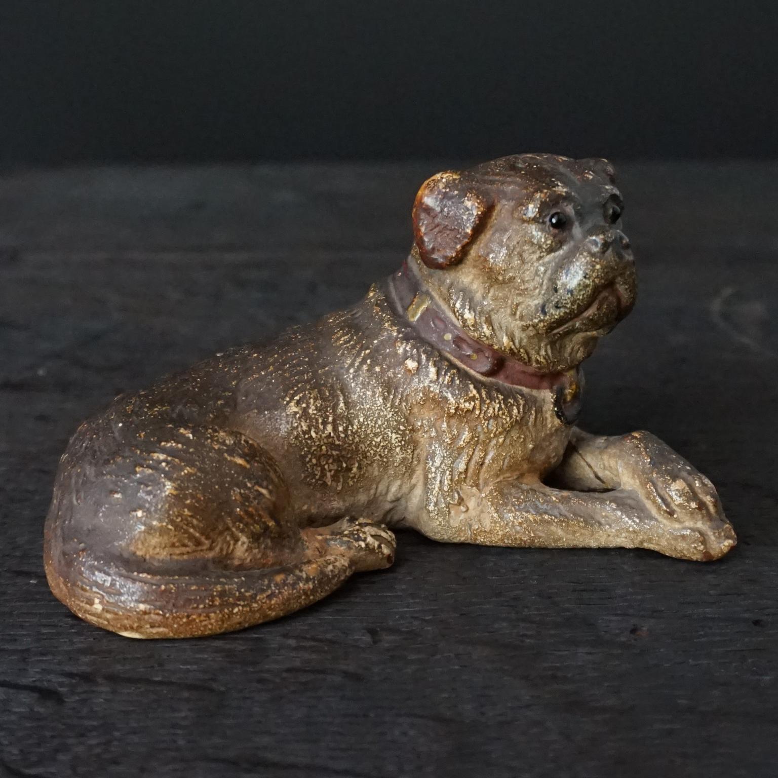 19th century Austrian terracotta lying mini pug dog with red collar and glass eyes.

I found this very lovely small Austrian cold hand painted terracotta model of a lying Pug dog with little painted red collar and black glass pin eyes. I could not