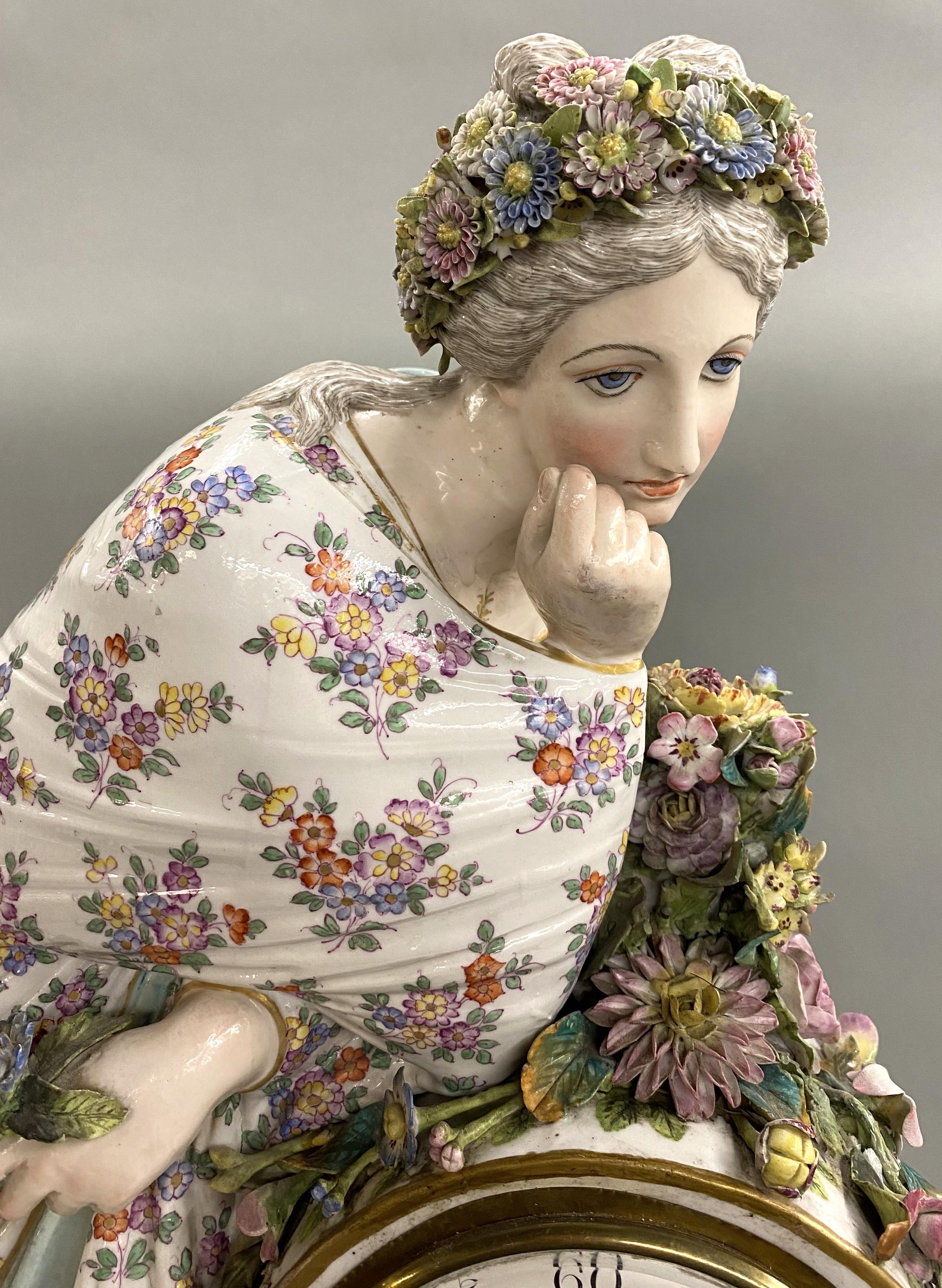 An exceptional porcelain figural clock with a woman adorned with flowers, probably Meissen, with a Roman numeral enamel painted clock face, brass works, and hand painted panels on the base with scenery and foliage. Dates to the 19th century, in good