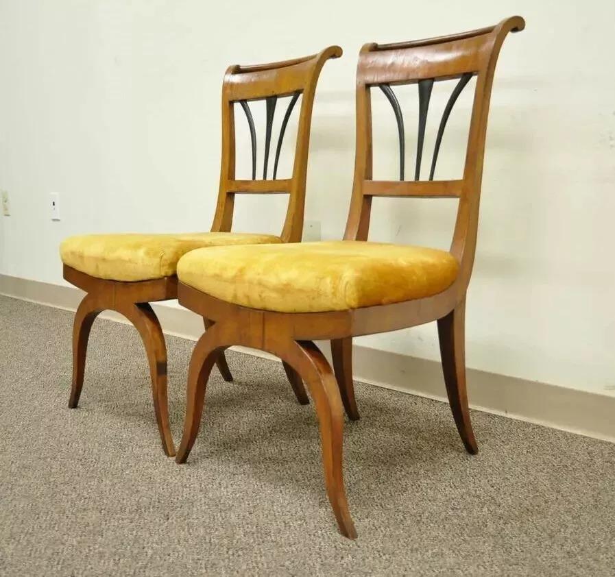 Coppia di sedie Biedermeier del XIX secolo con base in legno di Curule e ebanizzate. L'articolo è caratterizzato da eleganti gambe a sciabola, spalliere ebanizzate, schienali arrotolati, bellissime impiallacciature originali e cornici in legno