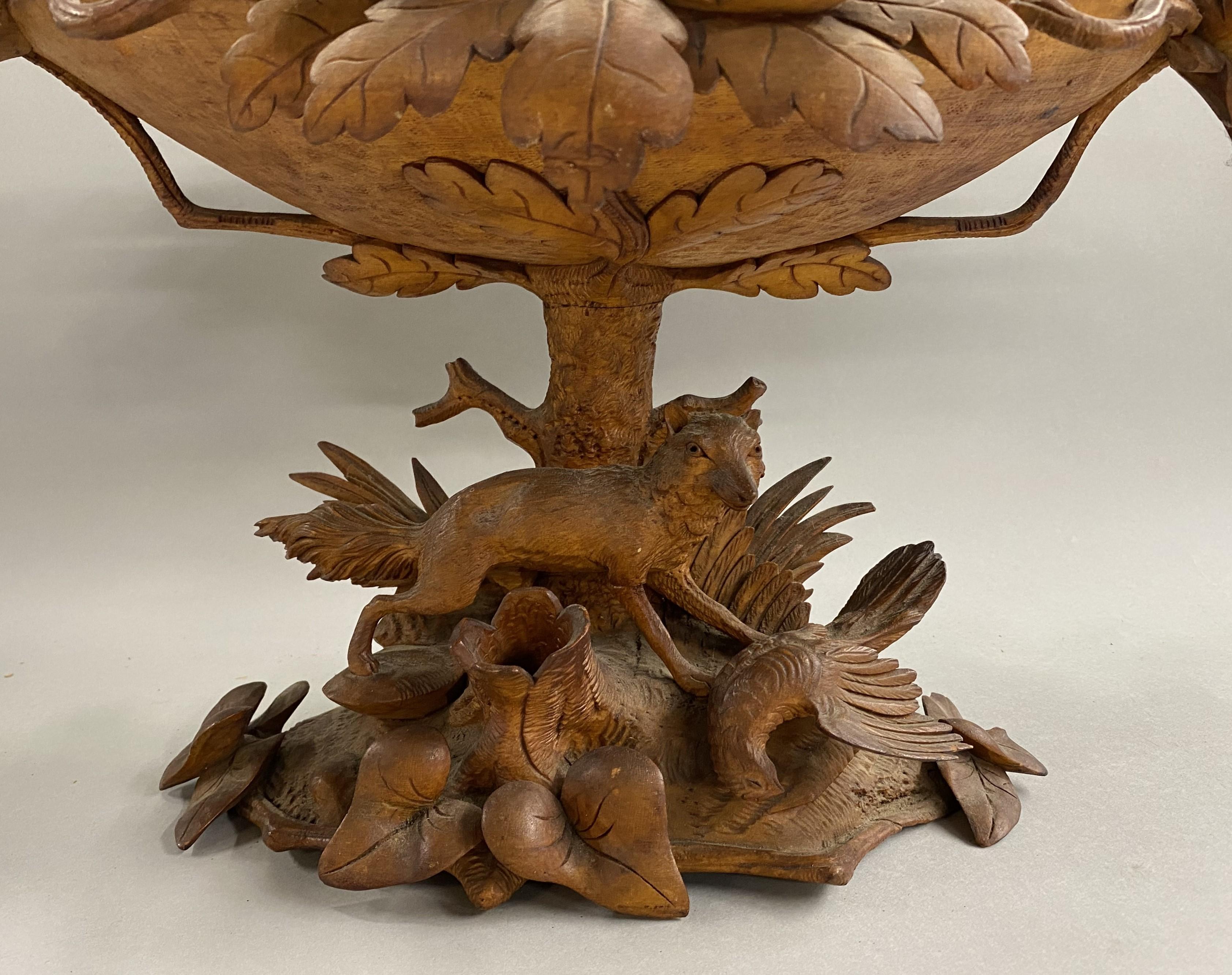 A wonderfully carved folk art Black Forest two piece compote with acorn and oak leaf bowl decoration, and a full carved fox and pheasant on the base around stumps and flora. Pencil inscribed on base “Mason”.  This exceptional piece dates to the late
