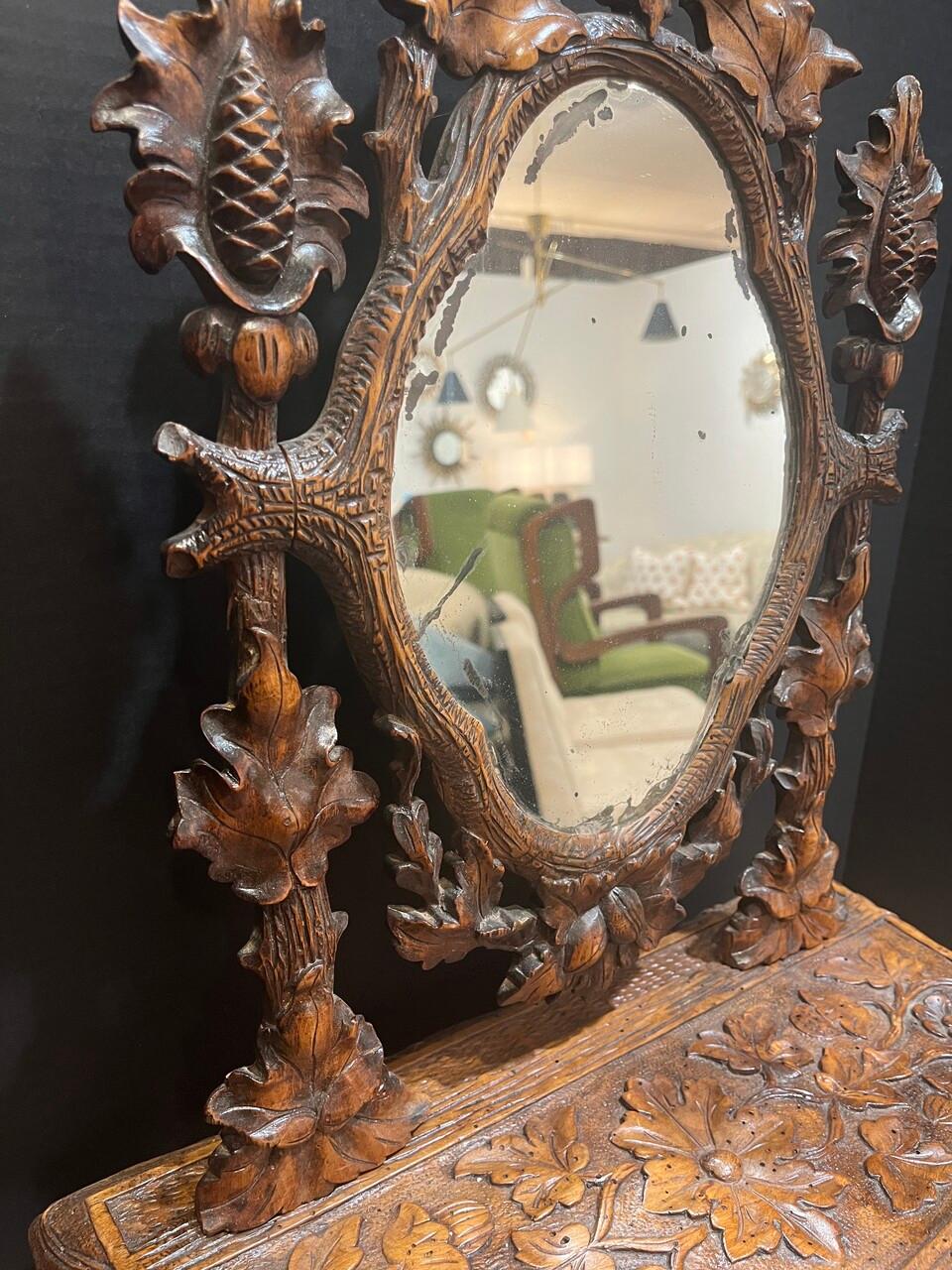 Elevate your decor with a touch of 19th-century beauty! This Carved French Oak Black Forest Tilting Tabletop Dresser is functional as well as elegant. Adorned with exquisite leaf, flower, and vine motifs, it boasts intricate craftsmanship. Complete