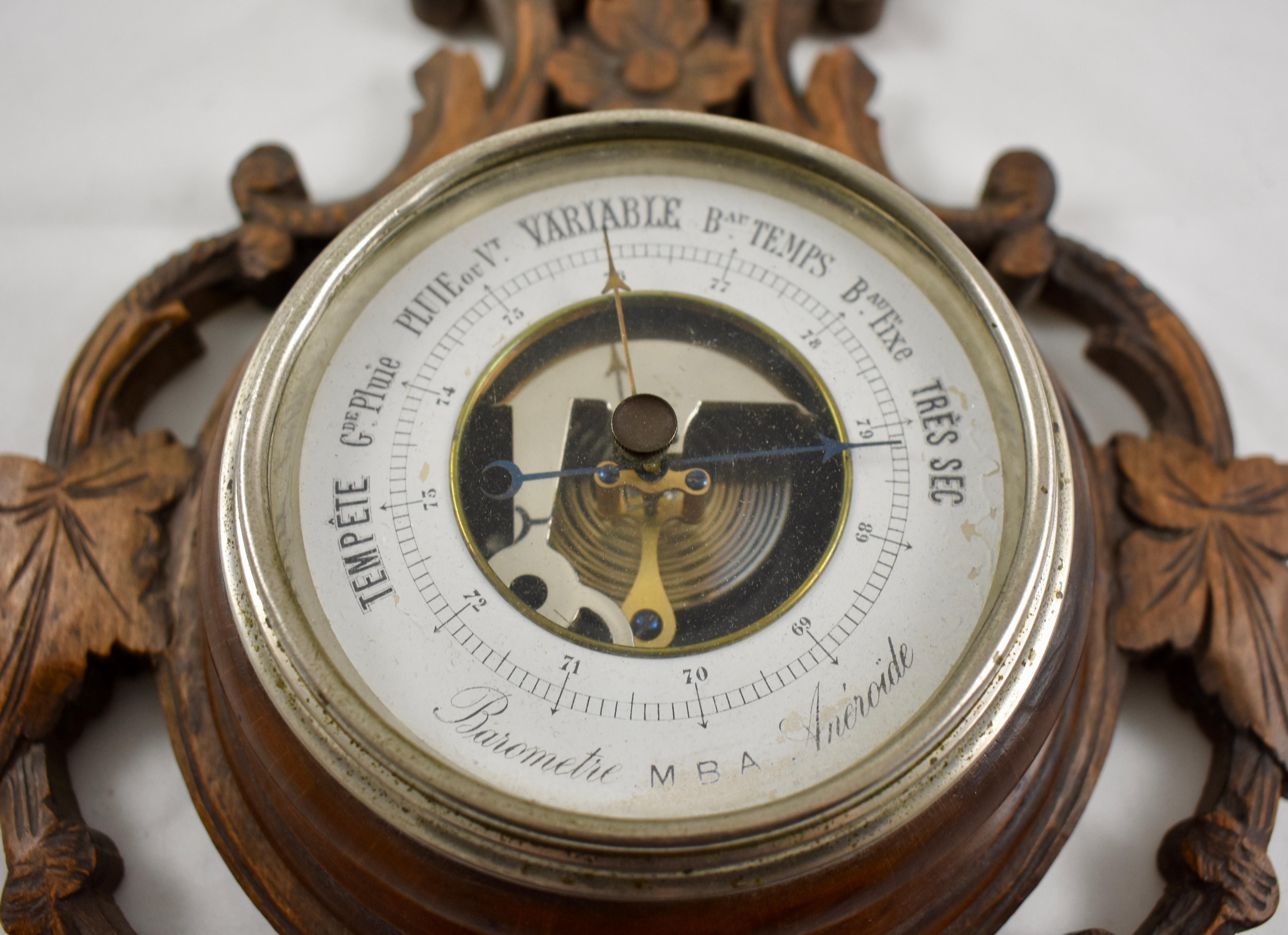 From Switzerland, a black forest wall barometer and thermometer set into a walnut frame, hand carved in a scrolled floral pattern, circa 1890-1900.

The thermometer shows a Celsius reading, the barometer dial is in French and shows the air