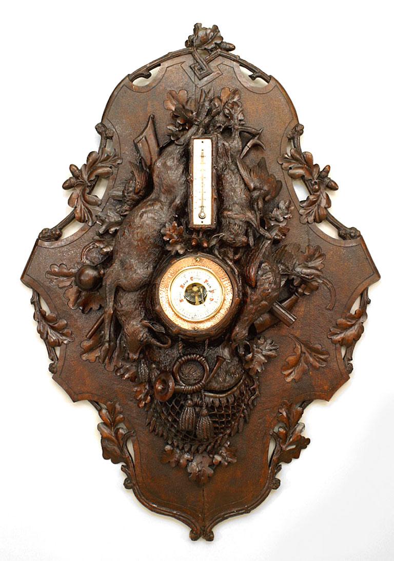 Rustikales Wandthermometer/Barometer aus Nussbaumholz (19. Jh.) mit Riemenwerkkartusche und einer kunstvoll geschnitzten Jagdtrophäe.
