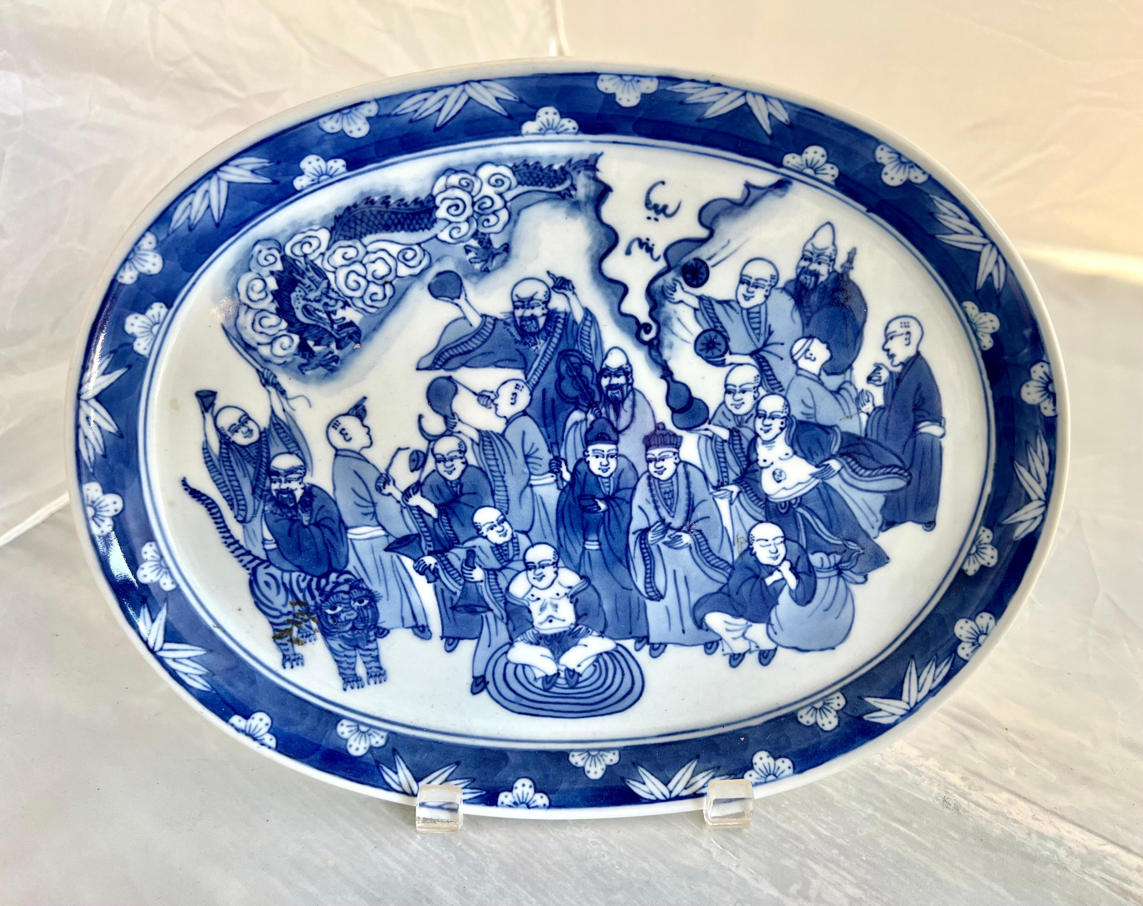 Le plat ovale bleu et blanc d'exportation chinoise avec des représentations de sages, d'un tigre et d'un dragon reflète probablement le symbolisme et les récits traditionnels chinois.  La combinaison de ces éléments pourrait avoir une signification