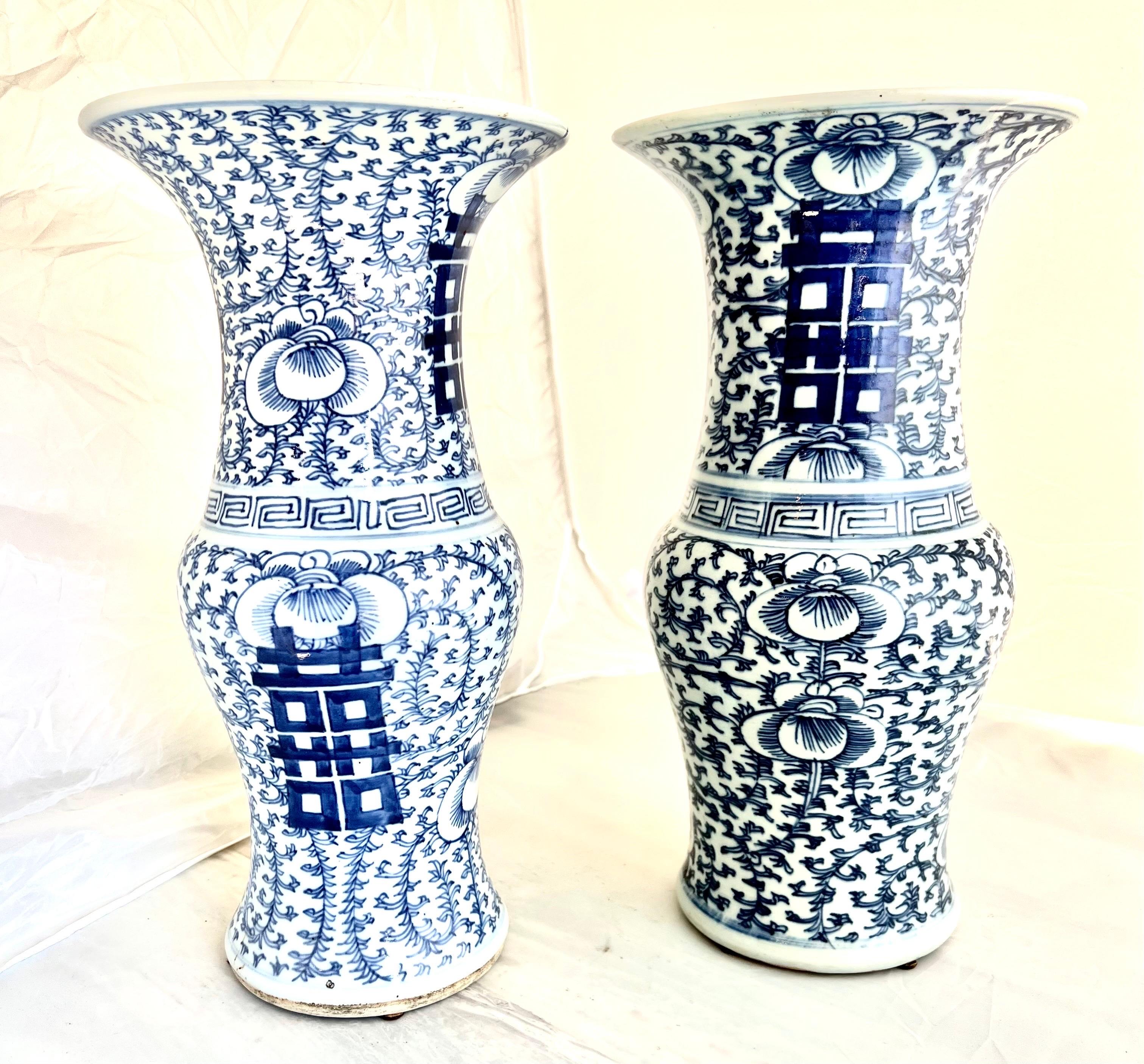 A pair of 19th-century blue and white Chinese export vases adorned with Chinese symbols and intricate vine designs showcase the classic elegance of Chinese ceramic artistry.  The blue and white color scheme, coupled with detailed depictions of