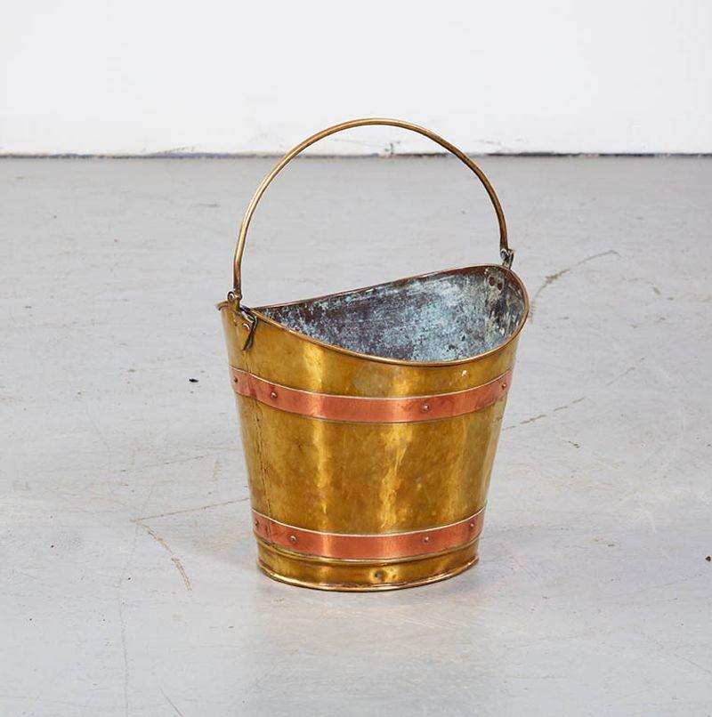 Attractive and unusual 19th century boat shaped bucket in brass with copper banding and brass carrying handle on spade hinges, useful for a waste-paper basket or for kindling next to a fireplace.