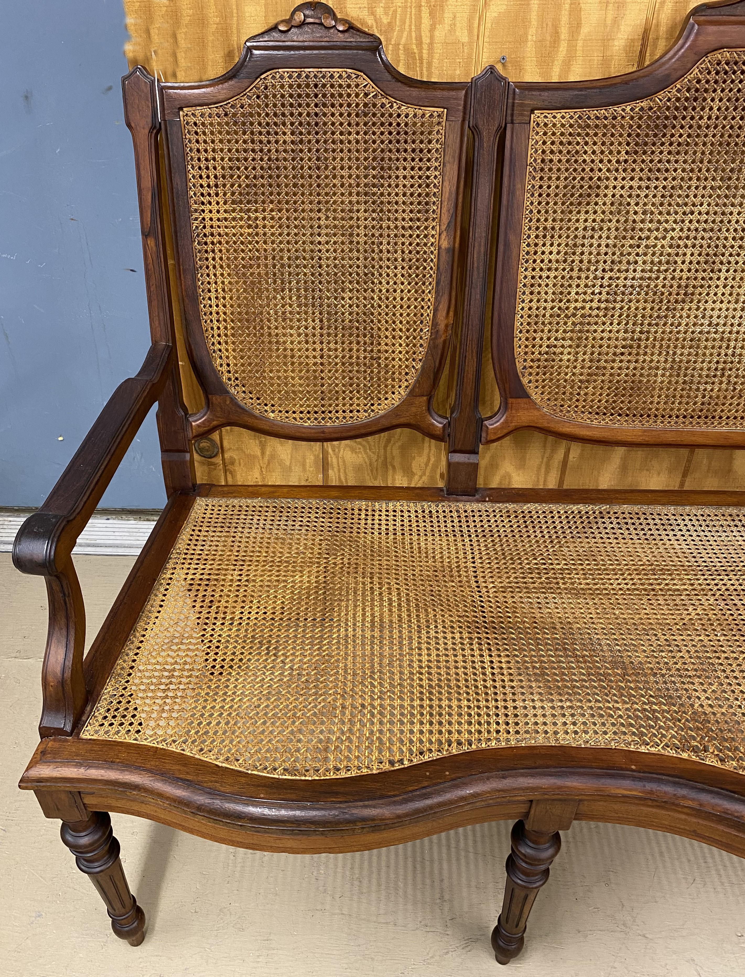 A nice example of a Brazilian hardwood settee, possibly jacaranda, with caned seat and back, carved crests, shaped seat rail, and tapered round turned and reeded legs. From the late 19th / early 20th century, in very good overall condition, with