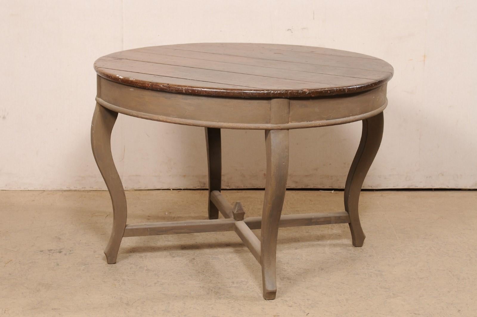 A Brazilian carved and painted peroba wood center table from the 19th century. This antique table from Brazil has a round-shaped top, over a plainly rounded skirt/apron, and raised on four curvy cabriole style legs. The legs are supported with a