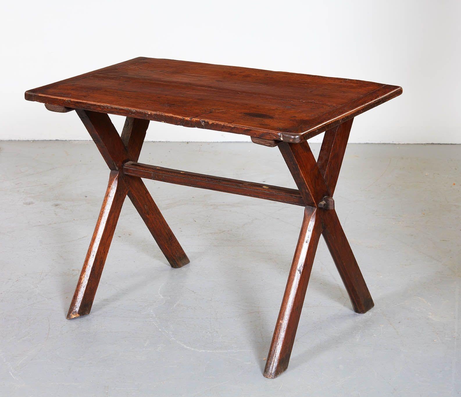 A 19th century oak tavern table having single board top with cleated ends on graphic X-frame base joined by peg and driven chocks and center stretcher. Graphic form, useful small scale, mellow patina and good nutty color.