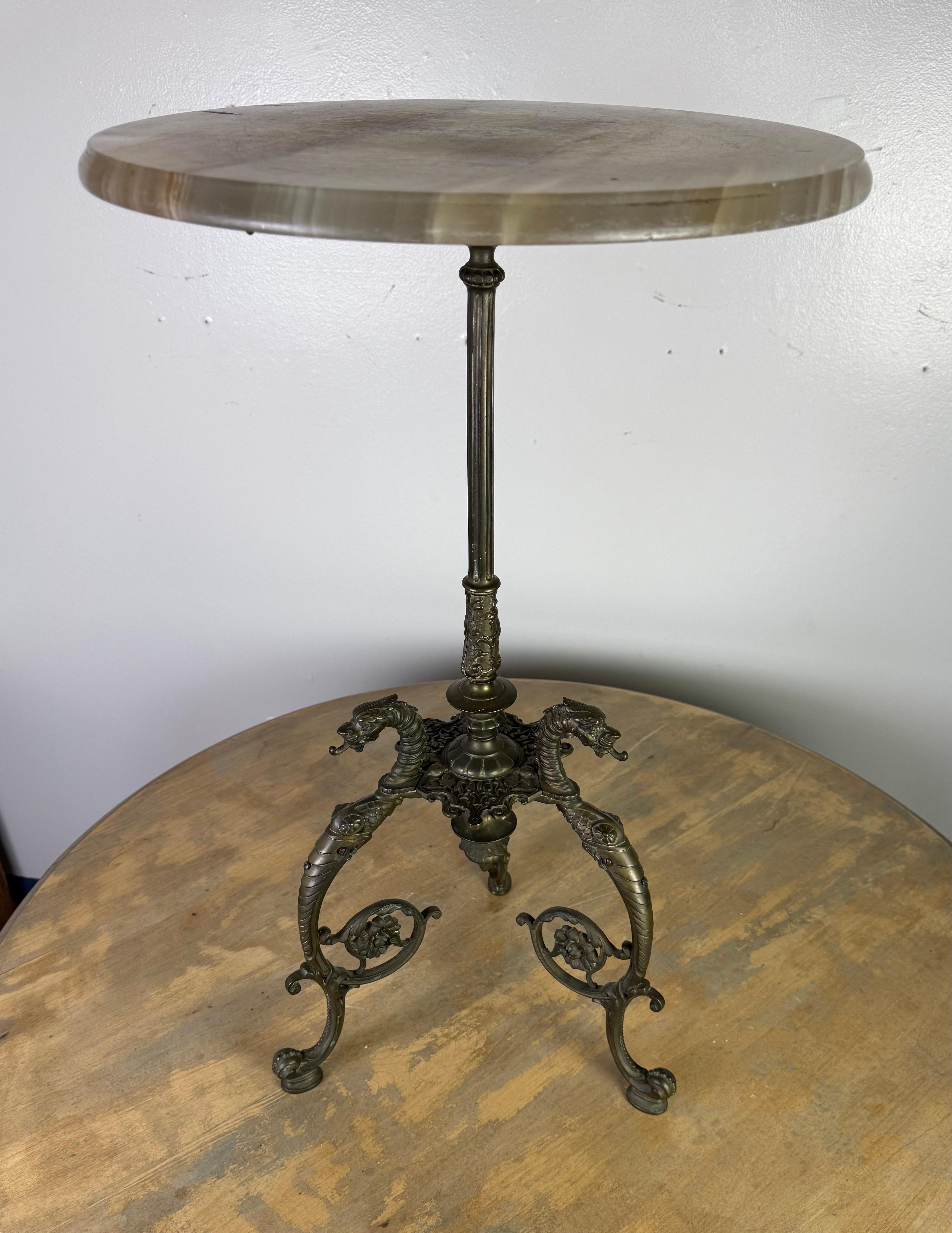 This striking German side table, dated 1898, showcases exceptional craftsmanship with a richly detailed bronze base and a smooth, polished onyx top. The round tabletop is made from natural onyx, featuring beautiful veining and a soft, translucent