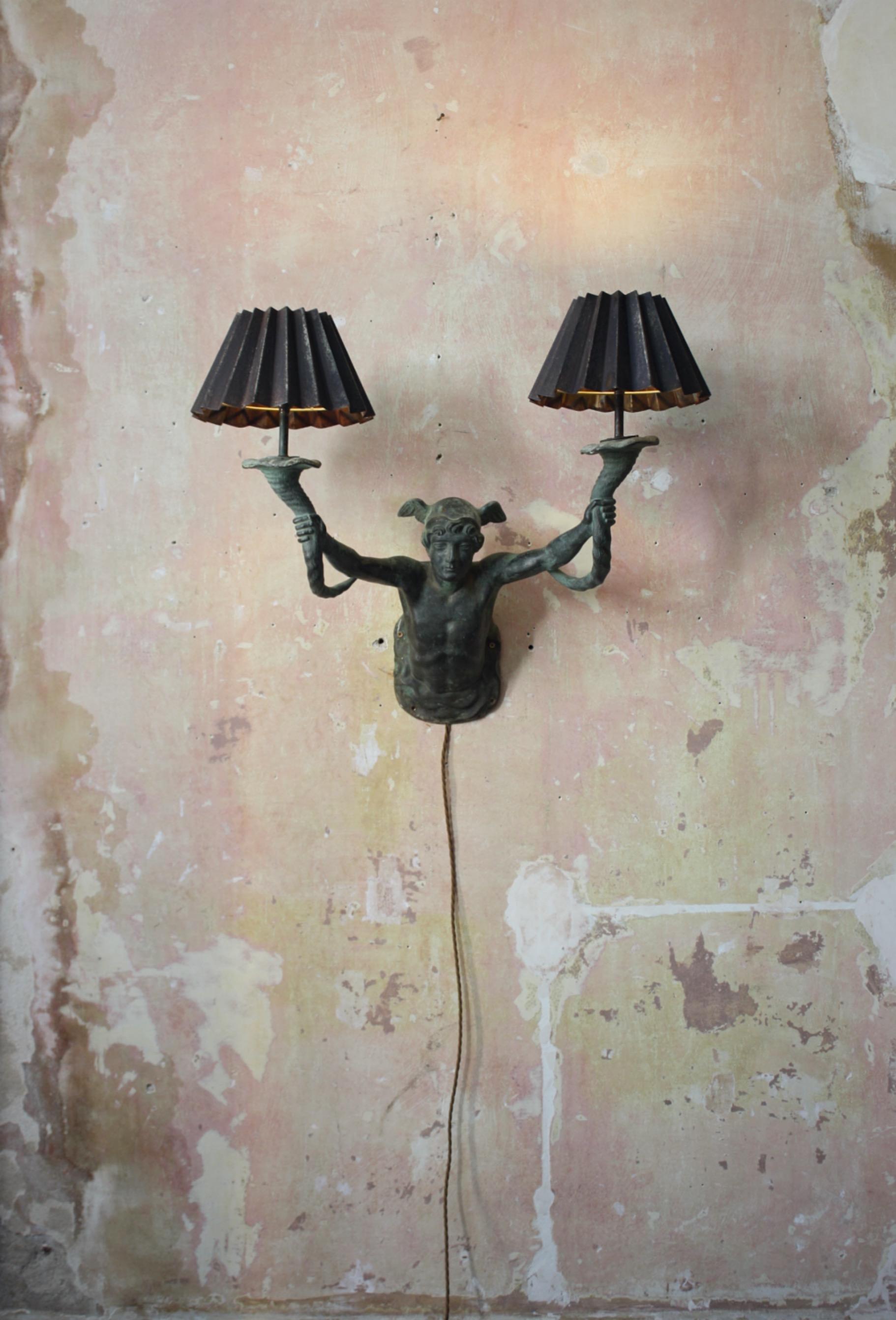 A mid to late 19th century French gas wall light, cast bronze depicting a well modelled Mercury holding aloft a pair of cornucopias.

Later rewired for electric, with pleated iron shades. Originaly used as a exterior light, with a wonderful