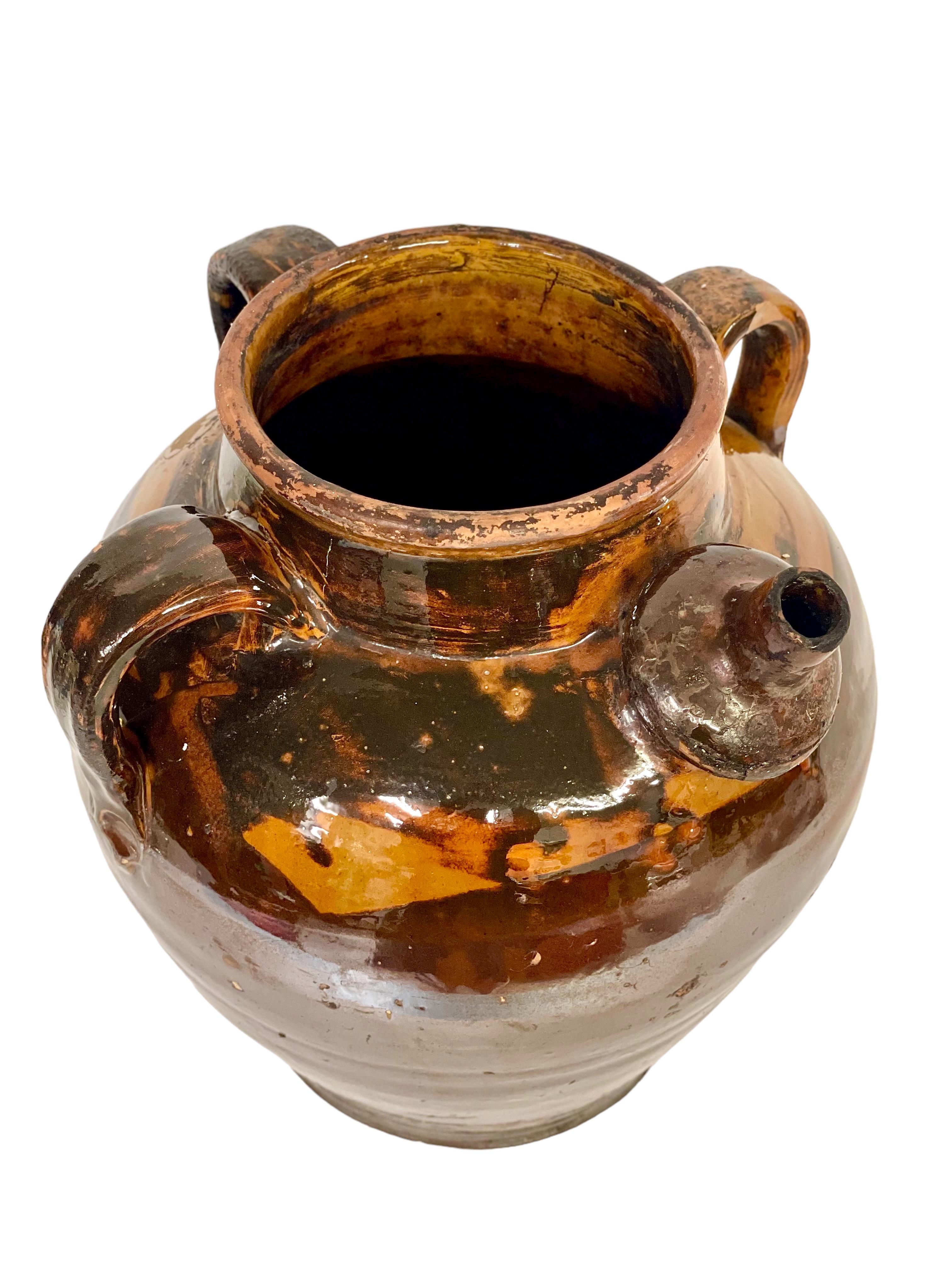 This antique French earthenware jug, with its fabulous rich brown and yellow glaze, dates from the 19th century, and would originally have been used to store nut oils or keep drinking water pleasantly cool. Featuring three handles and a