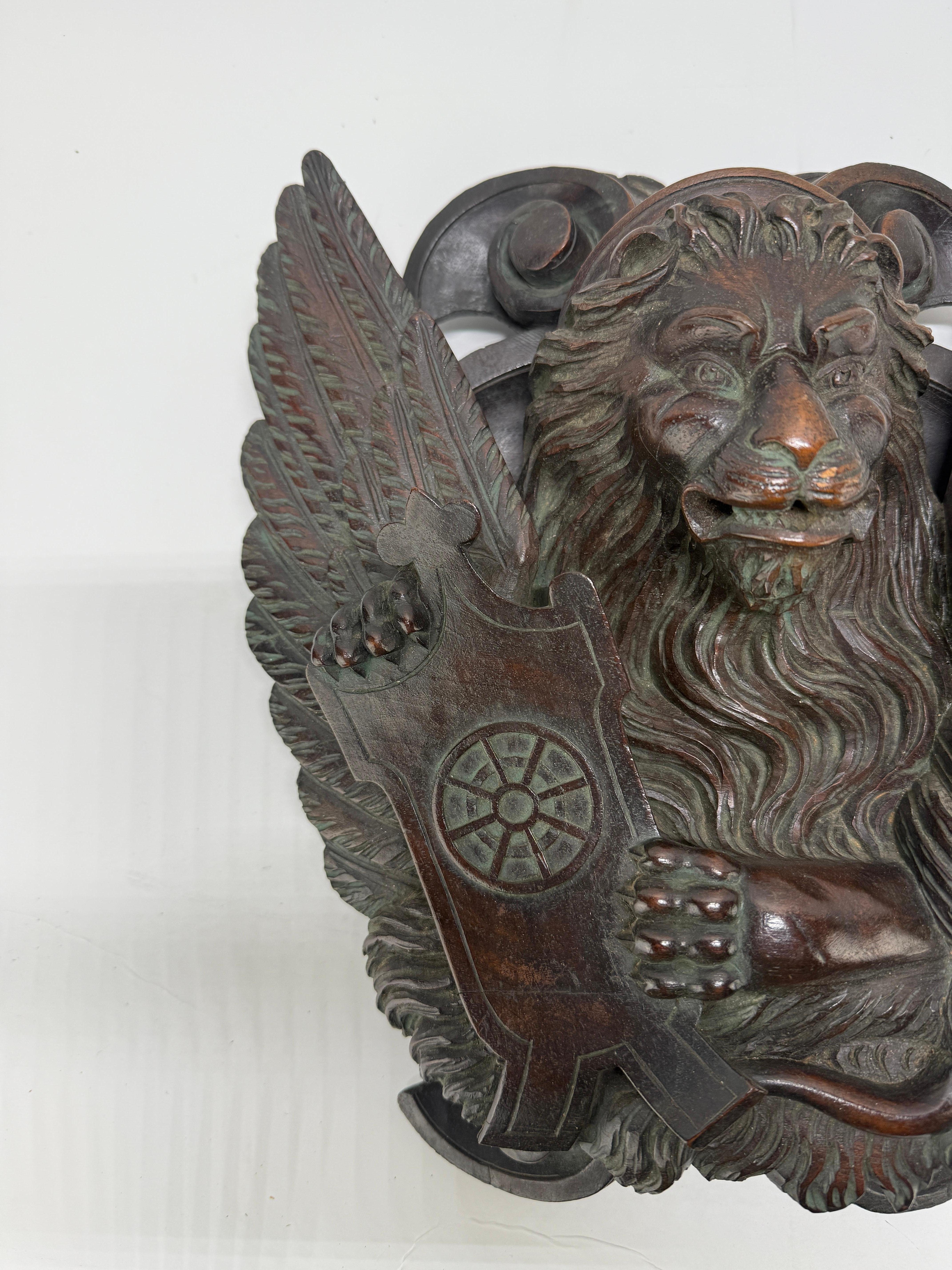 Carved Mahogany Relief of the Lion of Saint Mark with the Wheel of Saint Catherine

A finely carved and deeply modeled wooden relief, depicting the iconic Lion of Saint Mark in a striking frontal pose, executed in dense, dark-stained mahogany with