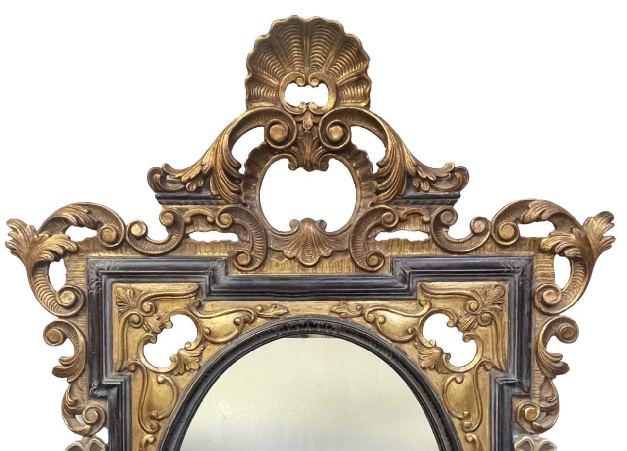 Remarquable miroir italien du XIXe siècle de style rococo, présentant une sculpture élaborée en noir et or, avec d'élégants motifs de volutes et des détails floraux. Le cadre du miroir est en outre embelli par des guirlandes suspendues délicatement