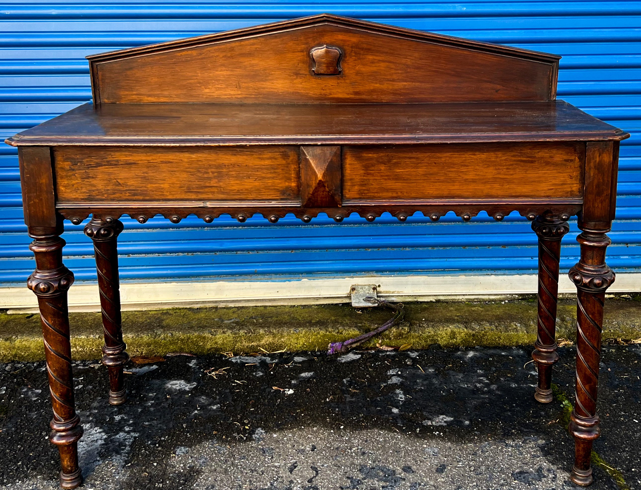 This is a stately piece! This is an antique carved English work table with a single pull out drawer. It is a great versatile size. It has a unique carved apron and a carved shield on the back panel. It is in very good antique condition. It is 30.5