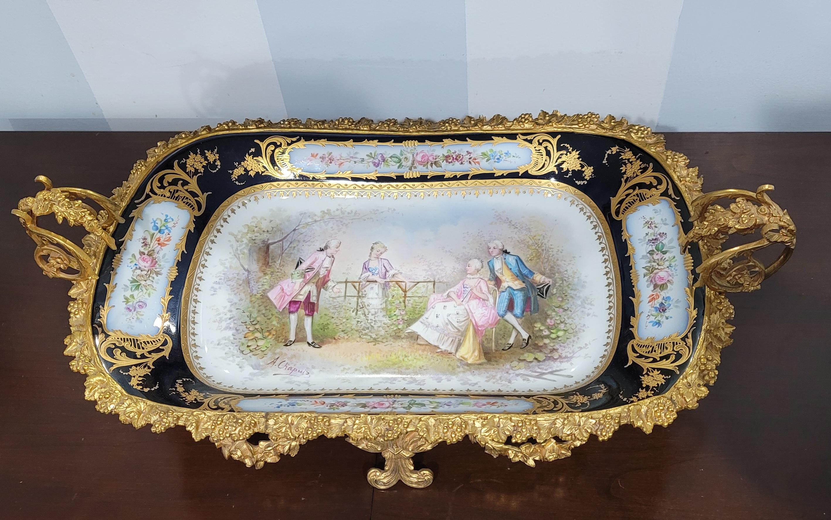 A 19th century Sevres hand-painted, cobalt & gilt porcelain ormolu mounted two-handle Centerpiece signed by French Artist A Chapuis. Intricate ormolu designs and decorations with acanthus leaves, flowers and other decoration.
Beautiful Large
