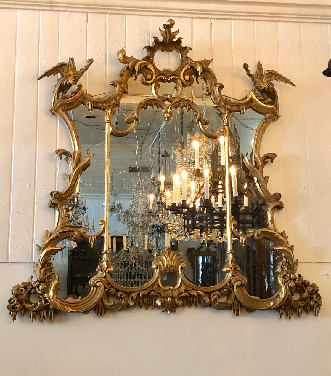 Enchanting Chinoiserie English Chippendale giltwood overmantel mirror. The Chippendale mirror is all craved giltwood with an open Center Cartouche flanked by a pair of HO HO Birds perched on pagoda roofs. This Classic Chinoiserie mirrors frame has