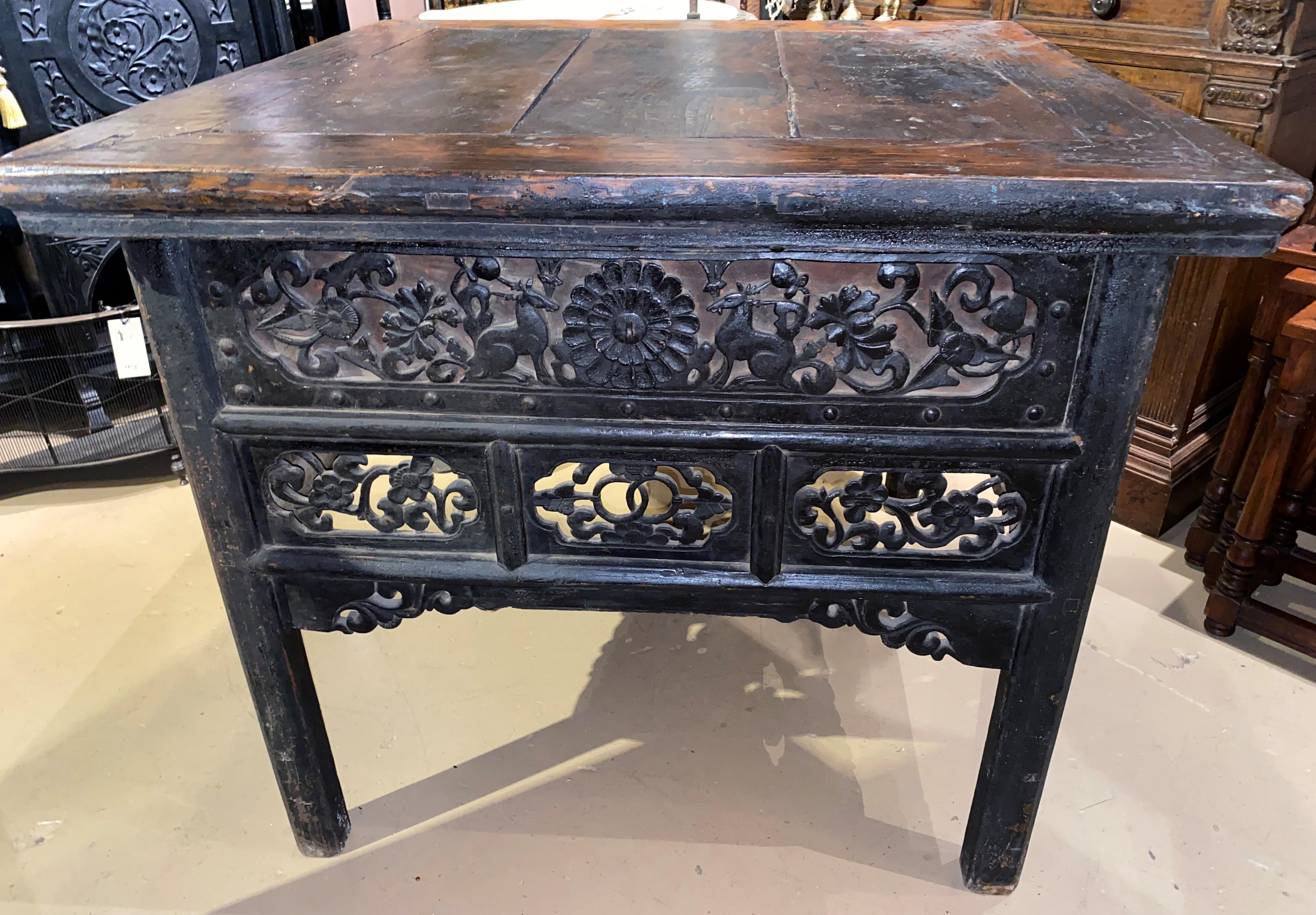 A fine example of a Chinese heavily carved hardwood center table, with a bordered three board top surmounting a pierce carved frieze on all four sides featuring deer, flowers, and scrollwork, all supported by four square legs. Dates to the 19th