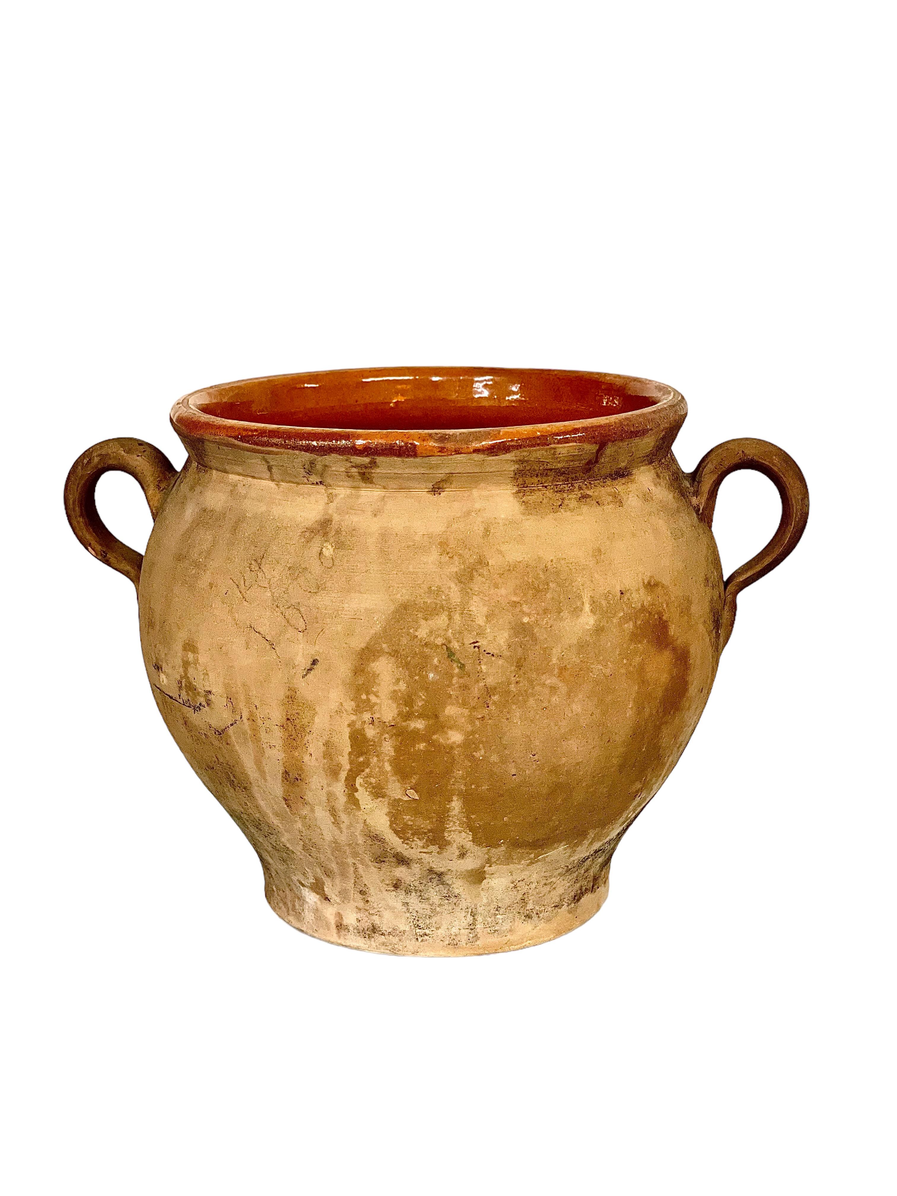 A charming terracotta 'Confit pot' with two side handles, glazed internally and full of character thanks to its authentic, time-worn patina. Once used in a southern French kitchen for the preservation of foodstuffs before the days of refrigeration,
