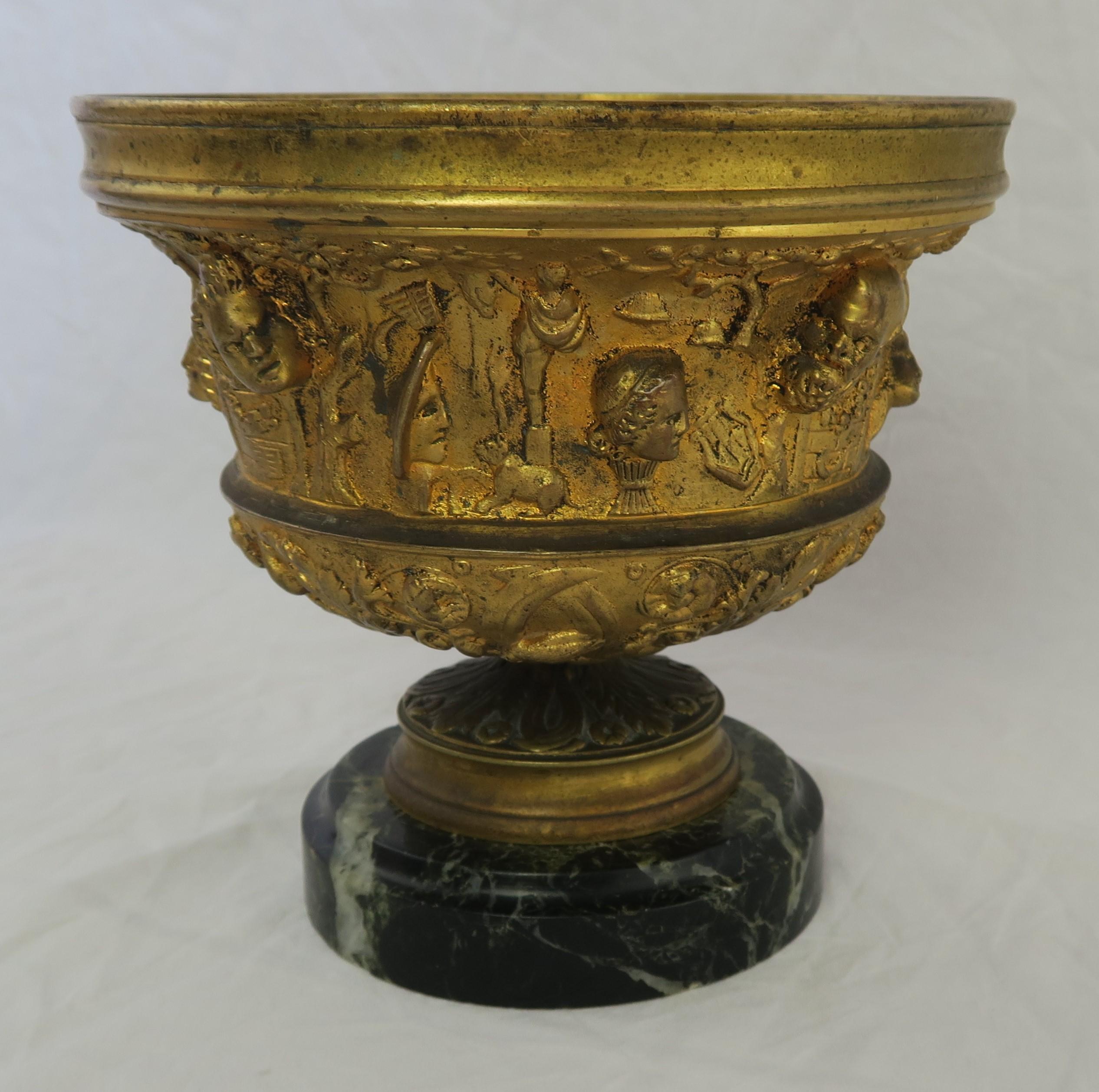 19th century cast bronze urn on marble base. The urn is adorned with intricate designs throughout.