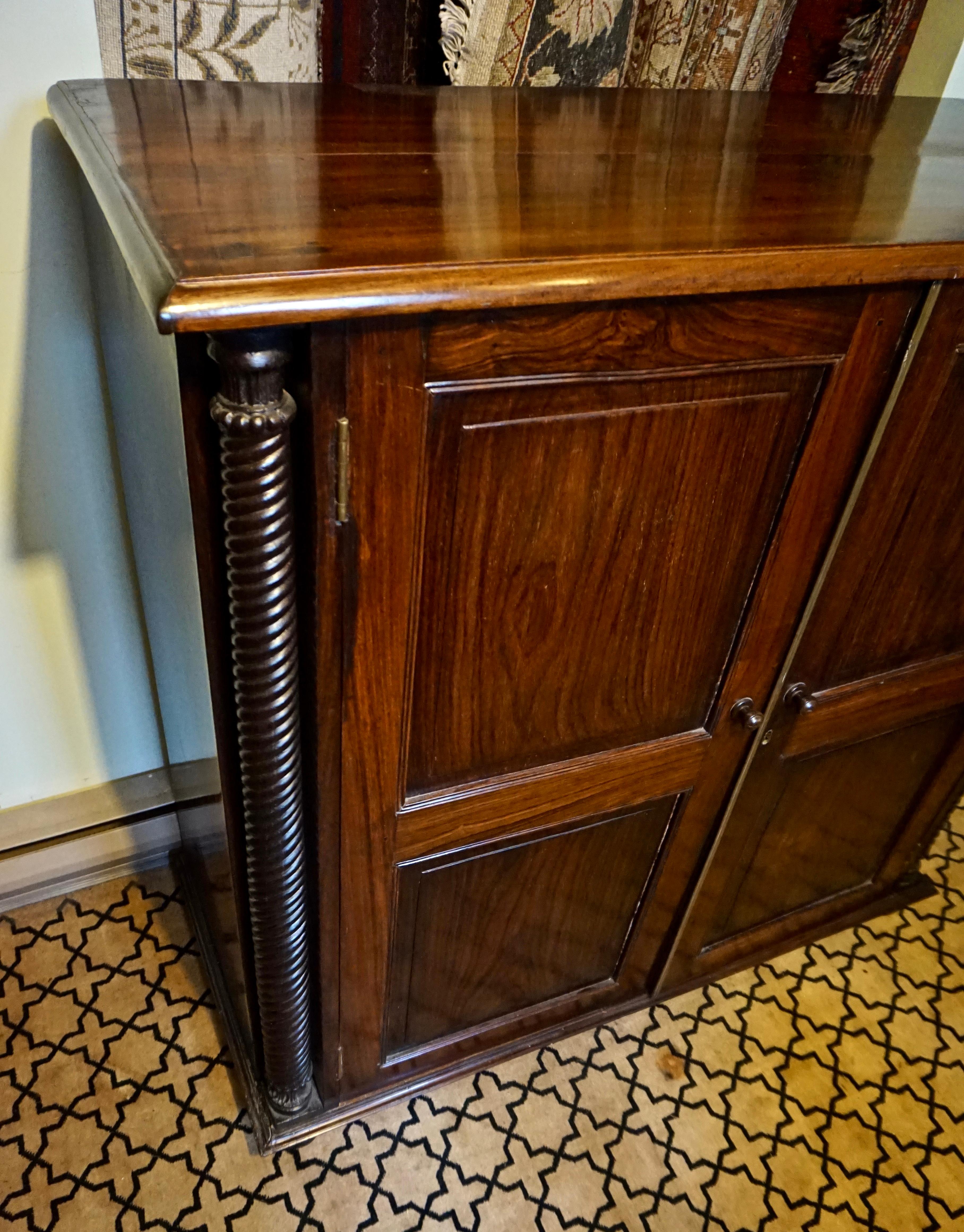 Uncompromisingly hand-crafted Colonial cabinet with barley twist columns and removable shelves Circa 1880-90. Constructed from solid Rosewood and sitting on bun feet framed by hand carved columns this cabinet has an elegant and stately feel. The